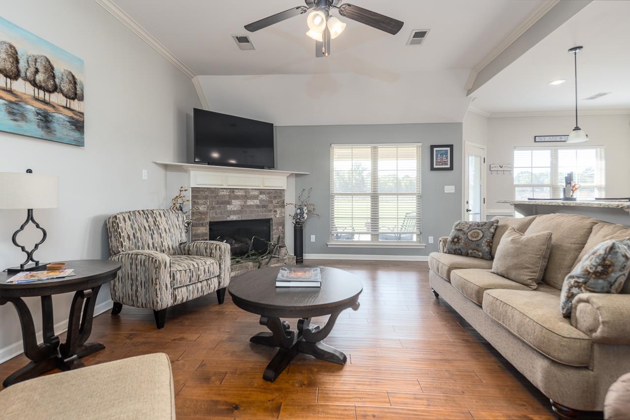 Great Room with hardwood / wood-style flooring, a tiled fireplace, crown molding, and a healthy amount of sunlight