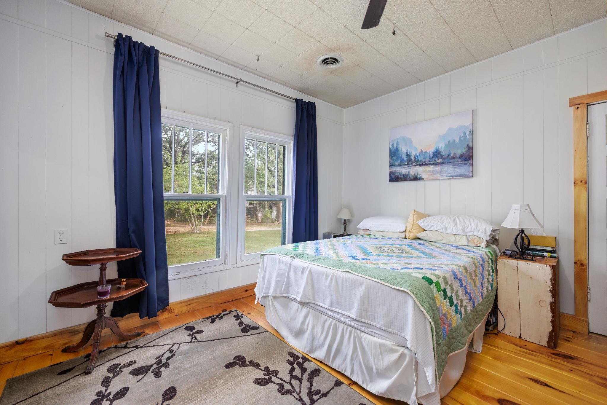 Bedroom with wood walls, light hardwood / wood-style flooring, and ceiling fan