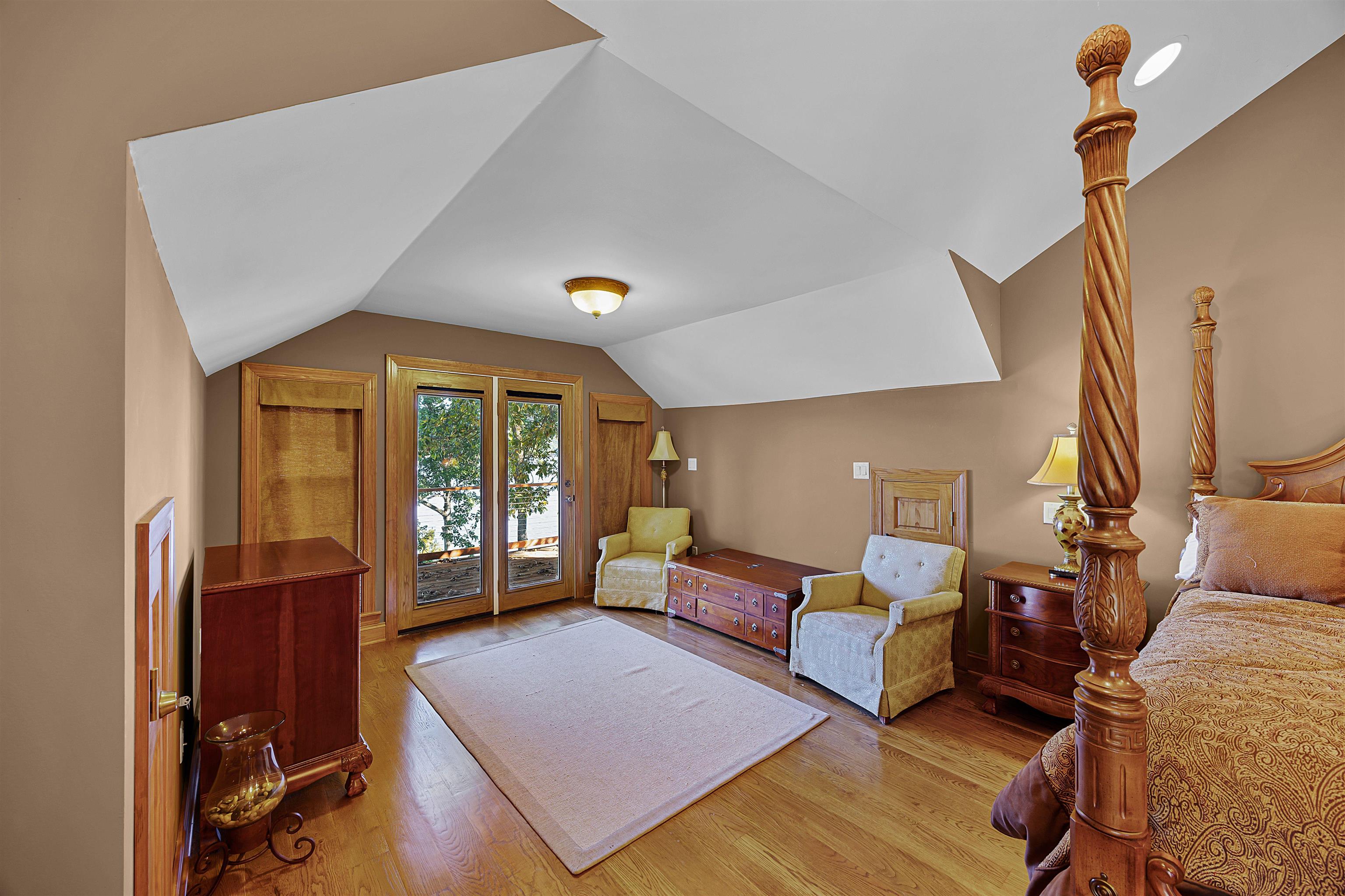 Bedroom with light hardwood / wood-style flooring, vaulted ceiling, and access to outside