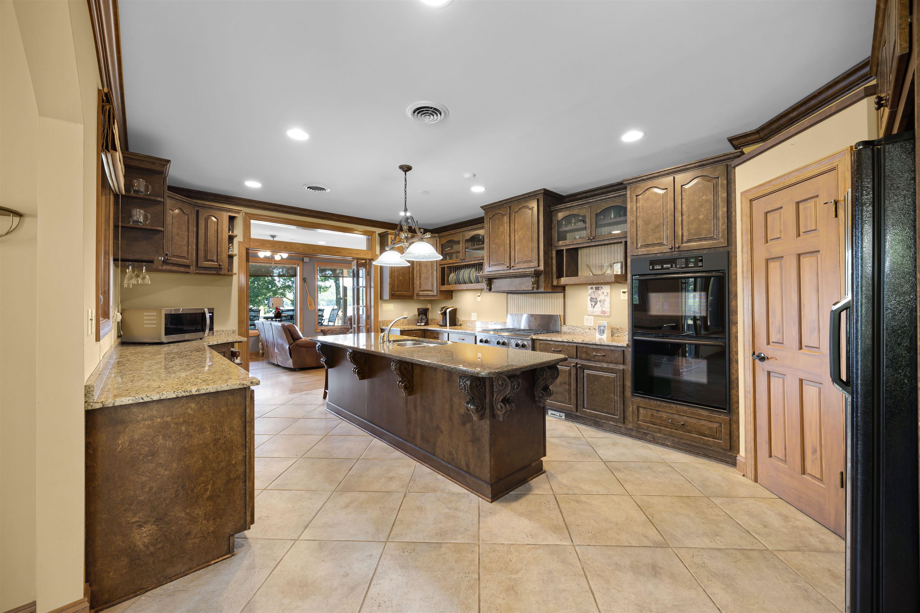 Kitchen featuring pendant lighting, light tile patterned flooring, sink, black appliances, and a kitchen breakfast bar