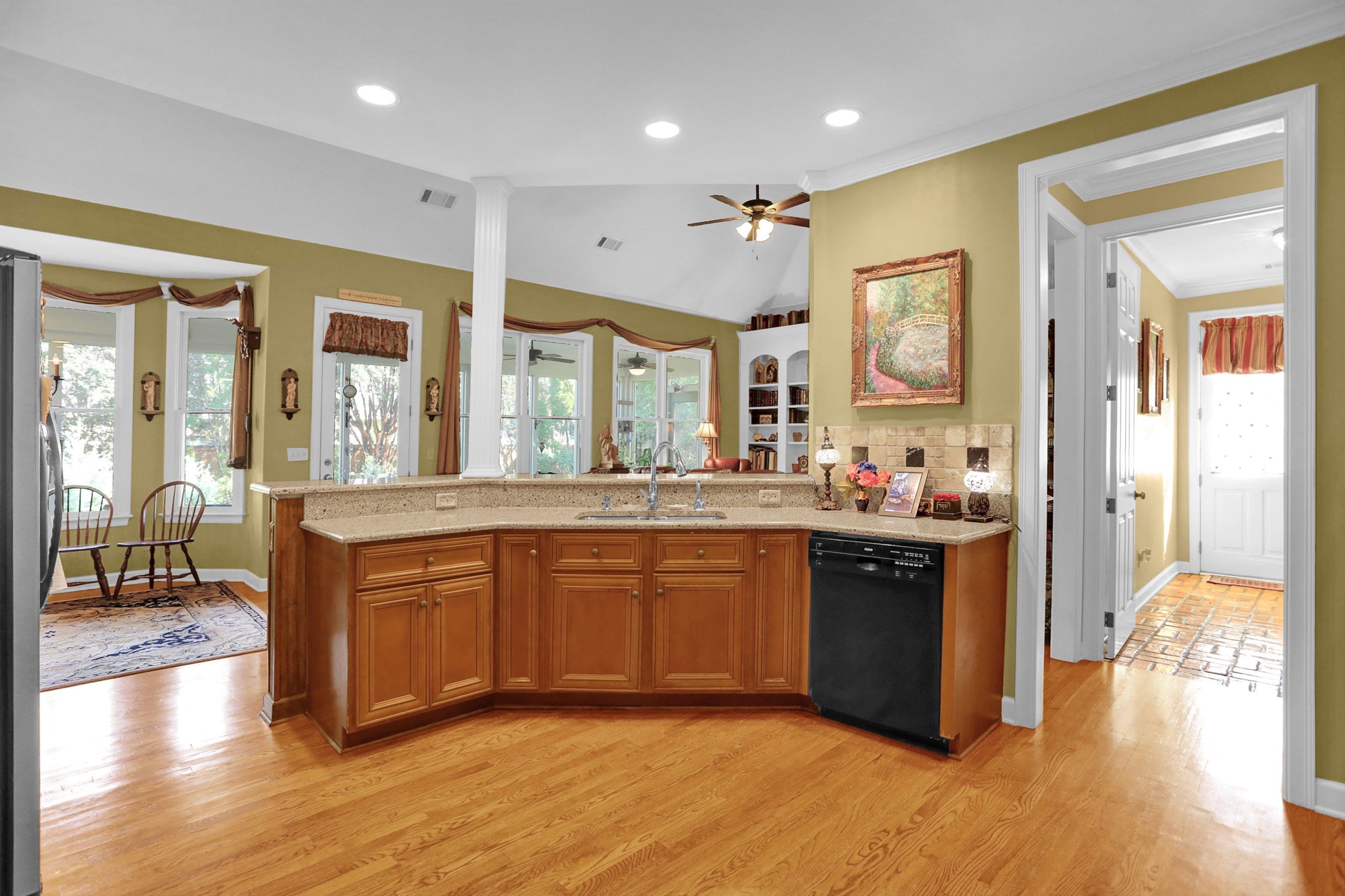 Kitchen with light hardwood / wood-style floors, sink, ornamental molding, dishwasher, and vaulted ceiling