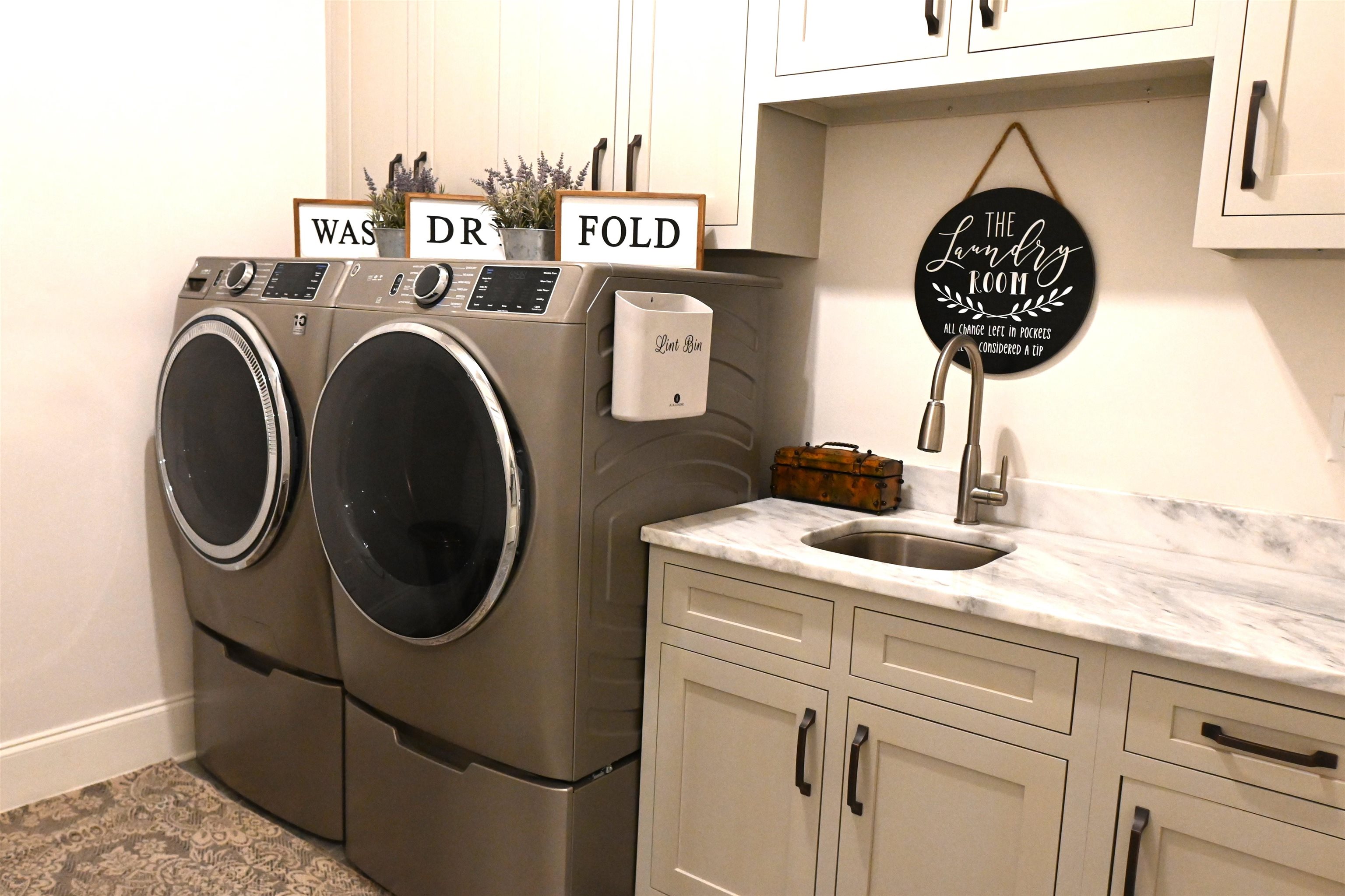 Laundry area featuring washing machine and dryer, cabinets, light tile patterned floors, and sink