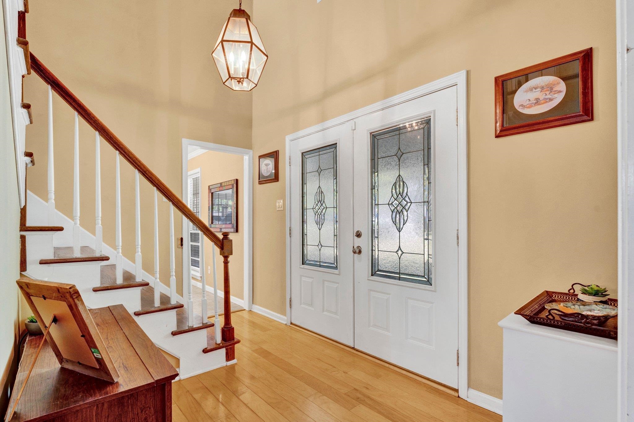 Foyer with wood-type flooring, a notable chandelier, and french doors