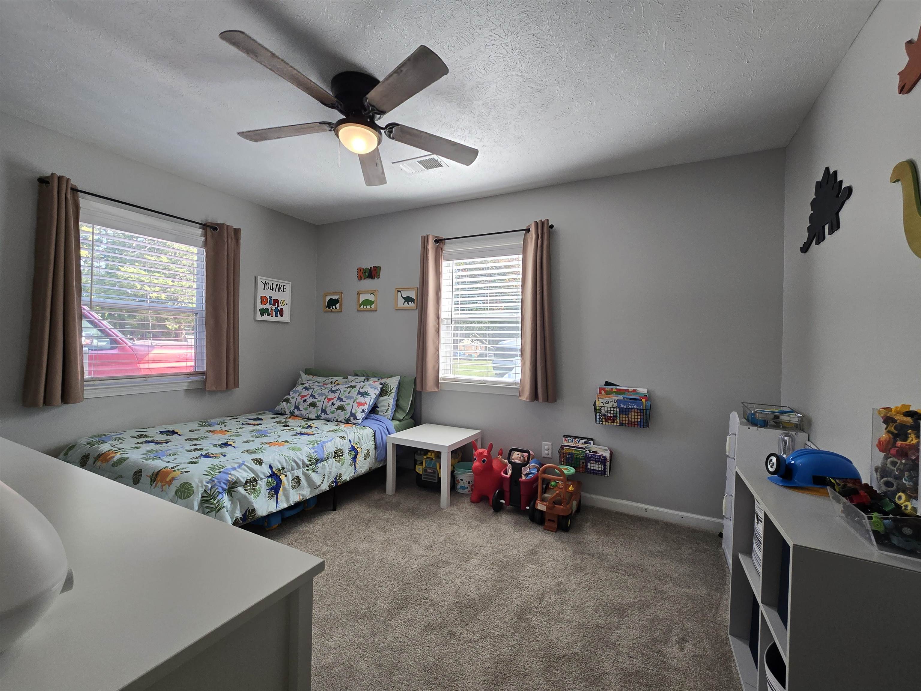 Bedroom with ceiling fan, a textured ceiling, and carpet