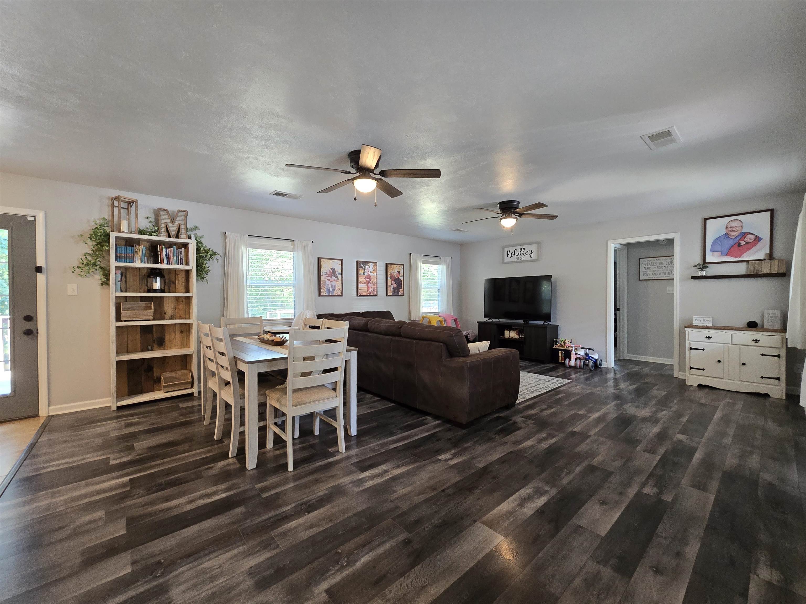 Living room featuring ceiling fan, dark wood-type flooring, and a textured ceiling