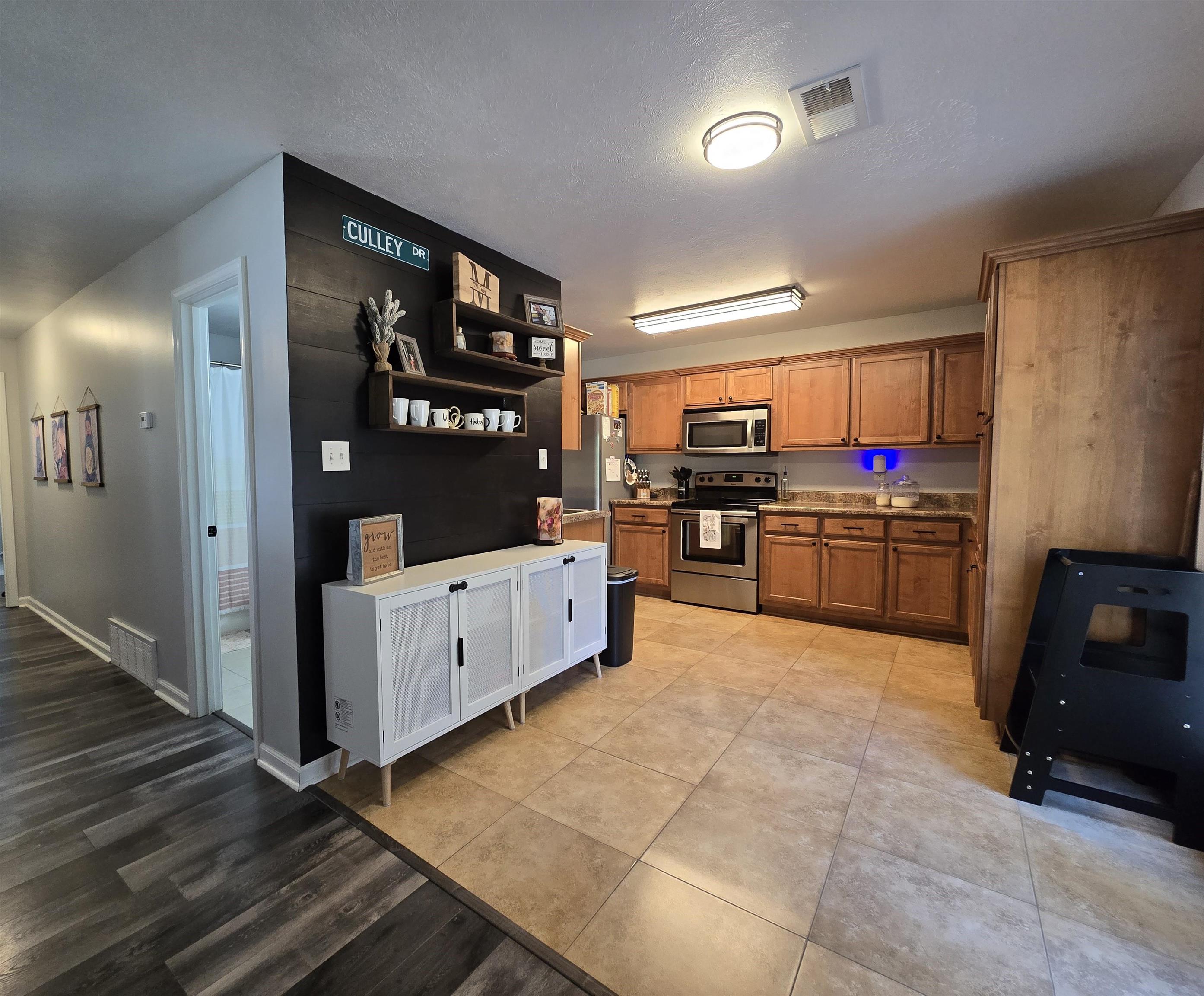 Kitchen with light hardwood / wood-style floors, appliances with stainless steel finishes, and a textured ceiling