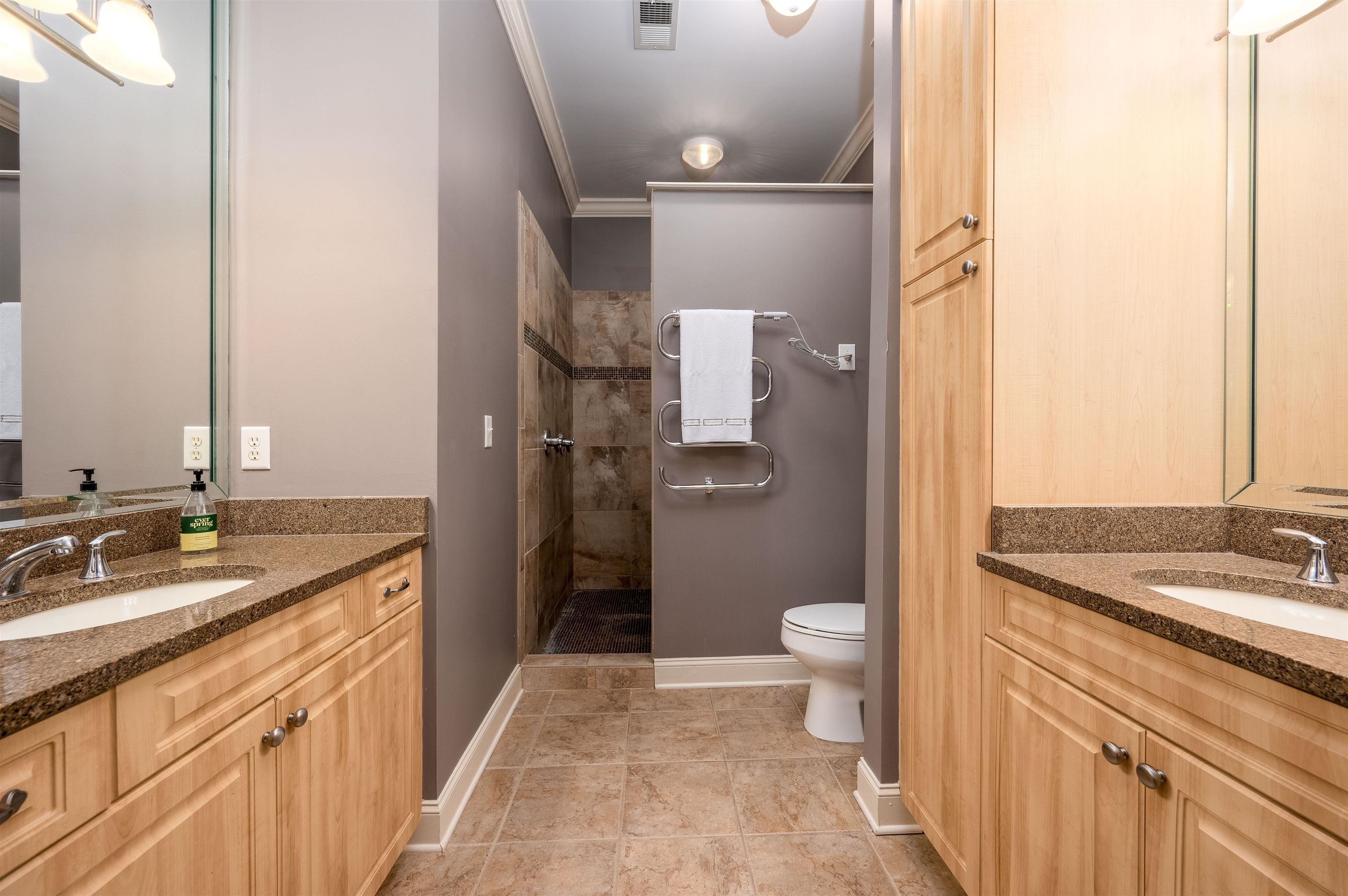 Bathroom featuring vanity, crown molding, toilet, and tiled shower