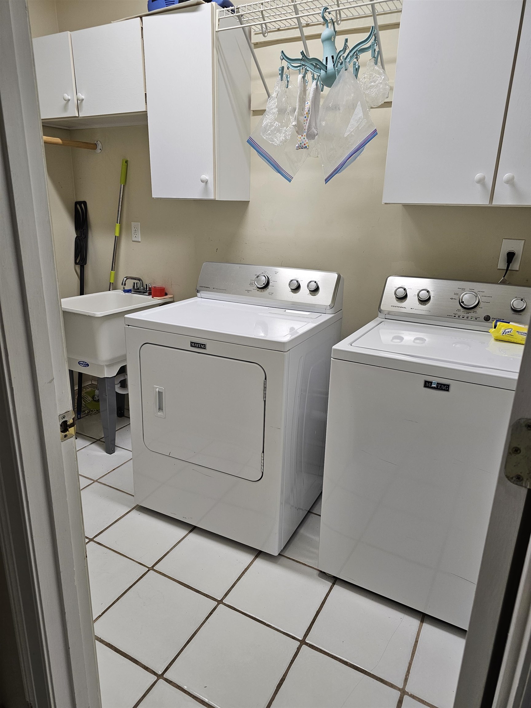 Laundry room with cabinets, light tile patterned floors, and washing machine and clothes dryer