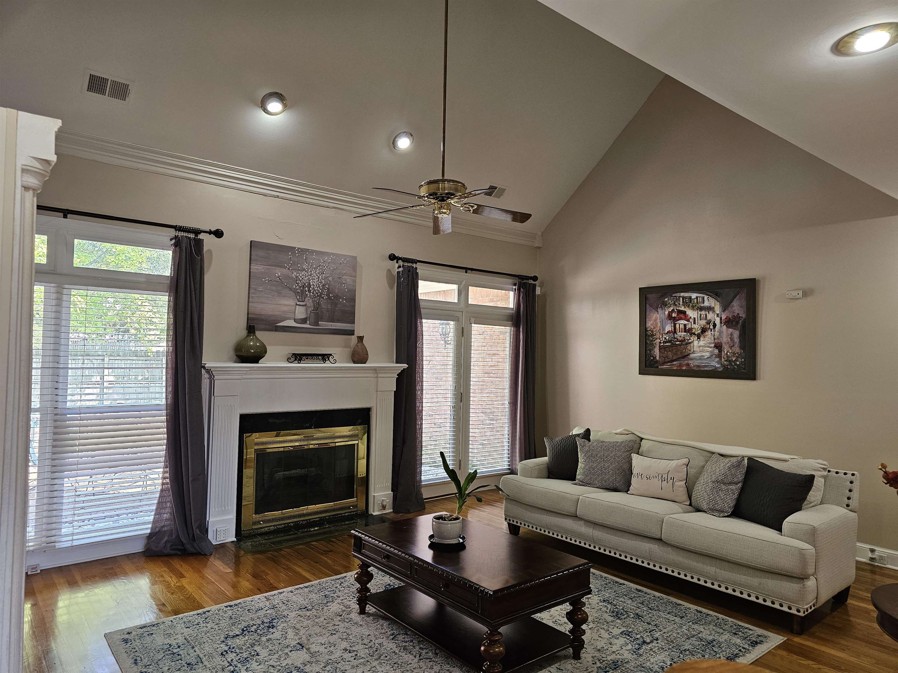 Living room featuring high vaulted ceiling, ceiling fan, and dark wood-type flooring