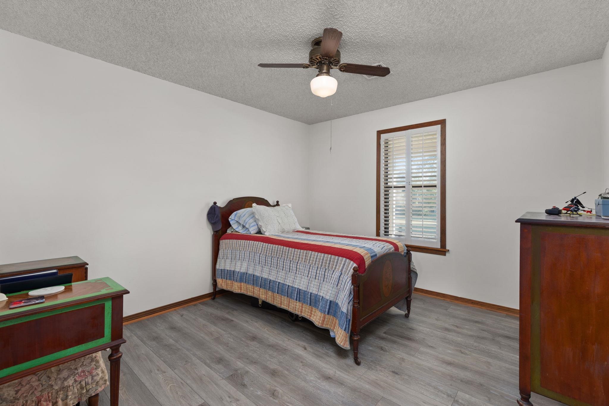 Bedroom featuring ceiling fan, light hardwood / wood-style floors, and a textured ceiling