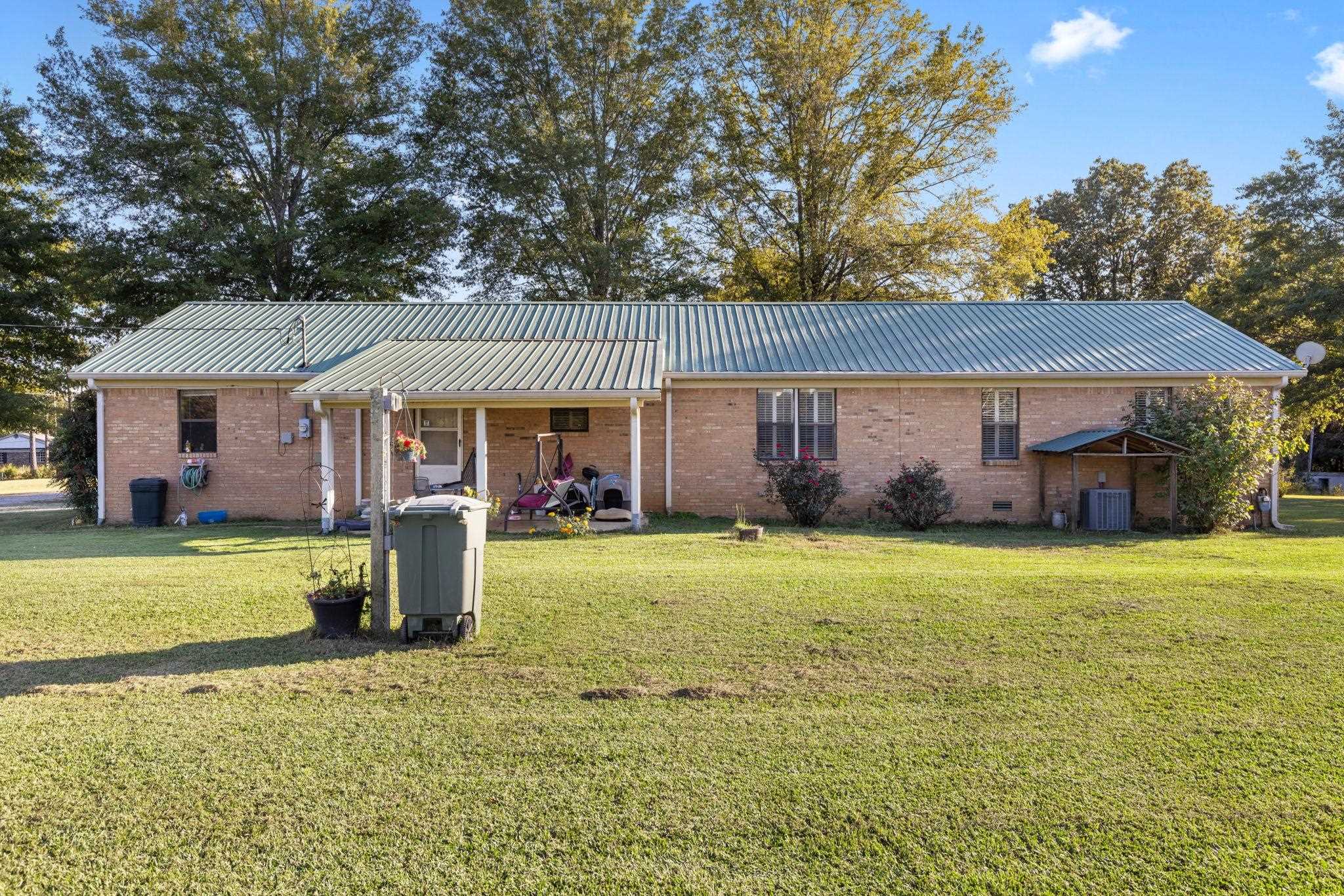 Back of property with central AC unit and a lawn