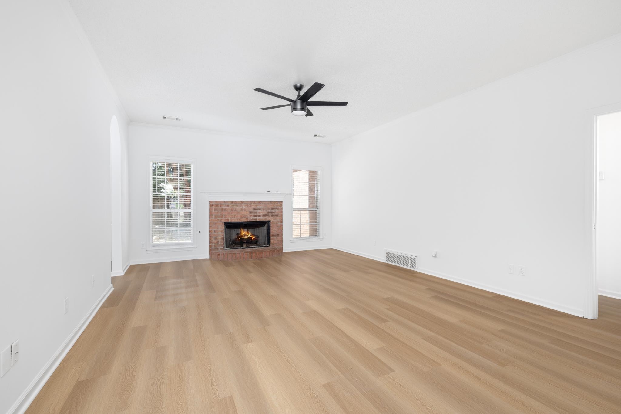 Unfurnished living room with ceiling fan, a fireplace, and light hardwood / wood-style floors