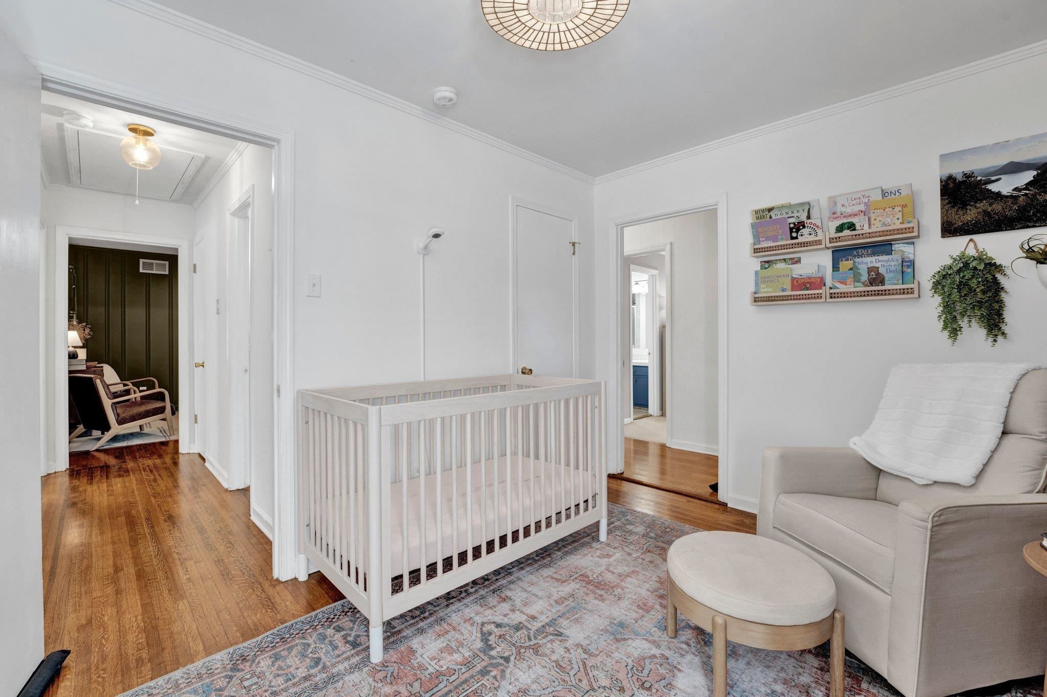 Bedroom featuring crown molding, a crib, and hardwood / wood-style flooring