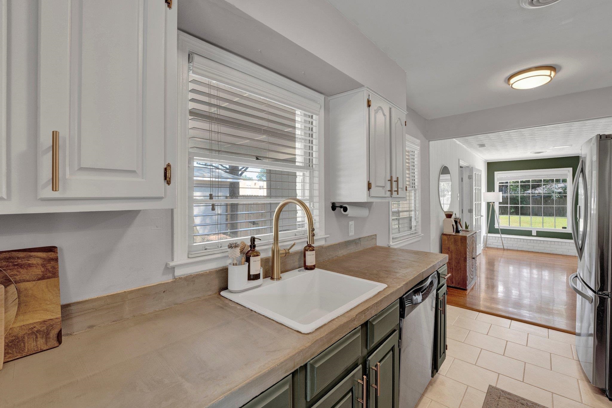 Kitchen with stainless steel appliances, white cabinets, sink, and light wood-type flooring