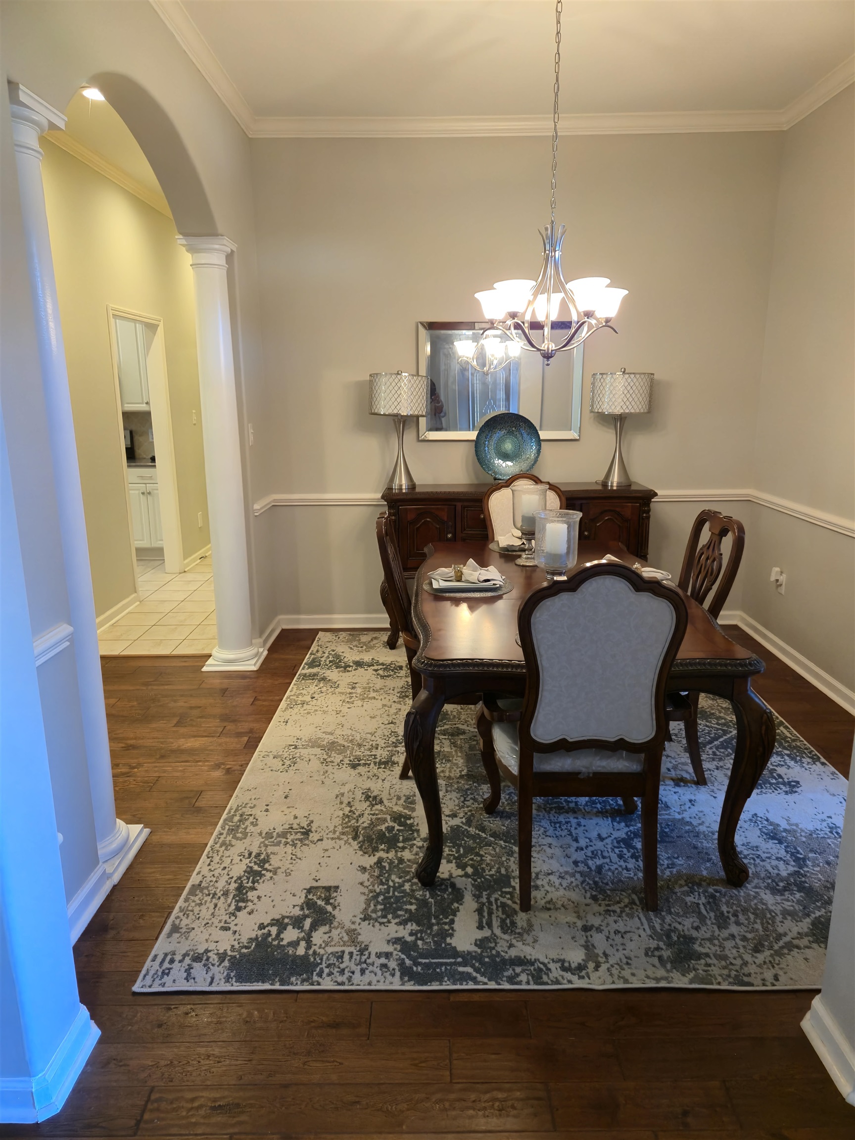 Dining space featuring decorative columns, crown molding, an inviting chandelier, and wood-type flooring