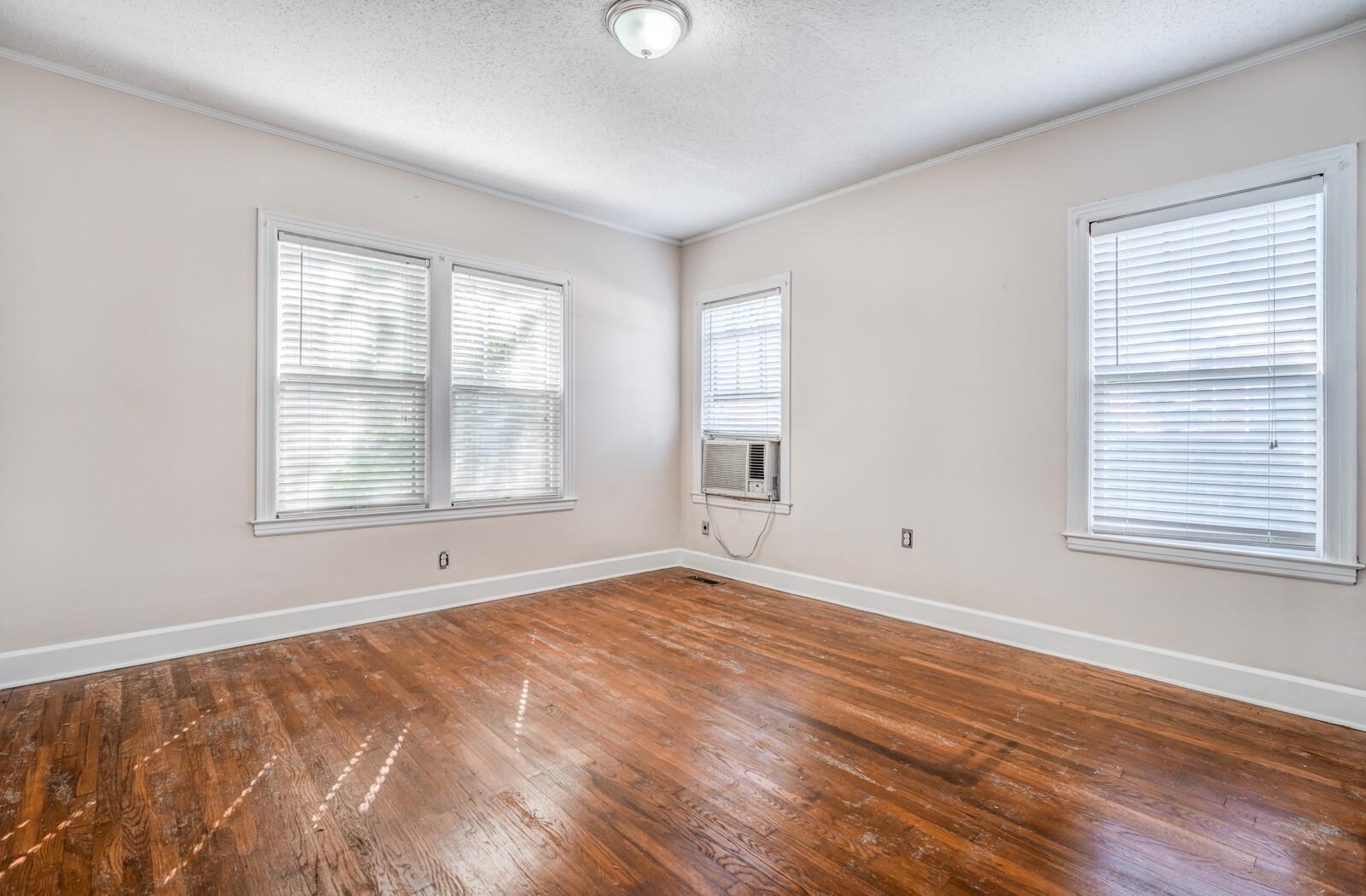 Empty room with wood-type flooring, a textured ceiling, plenty of natural light, and crown molding