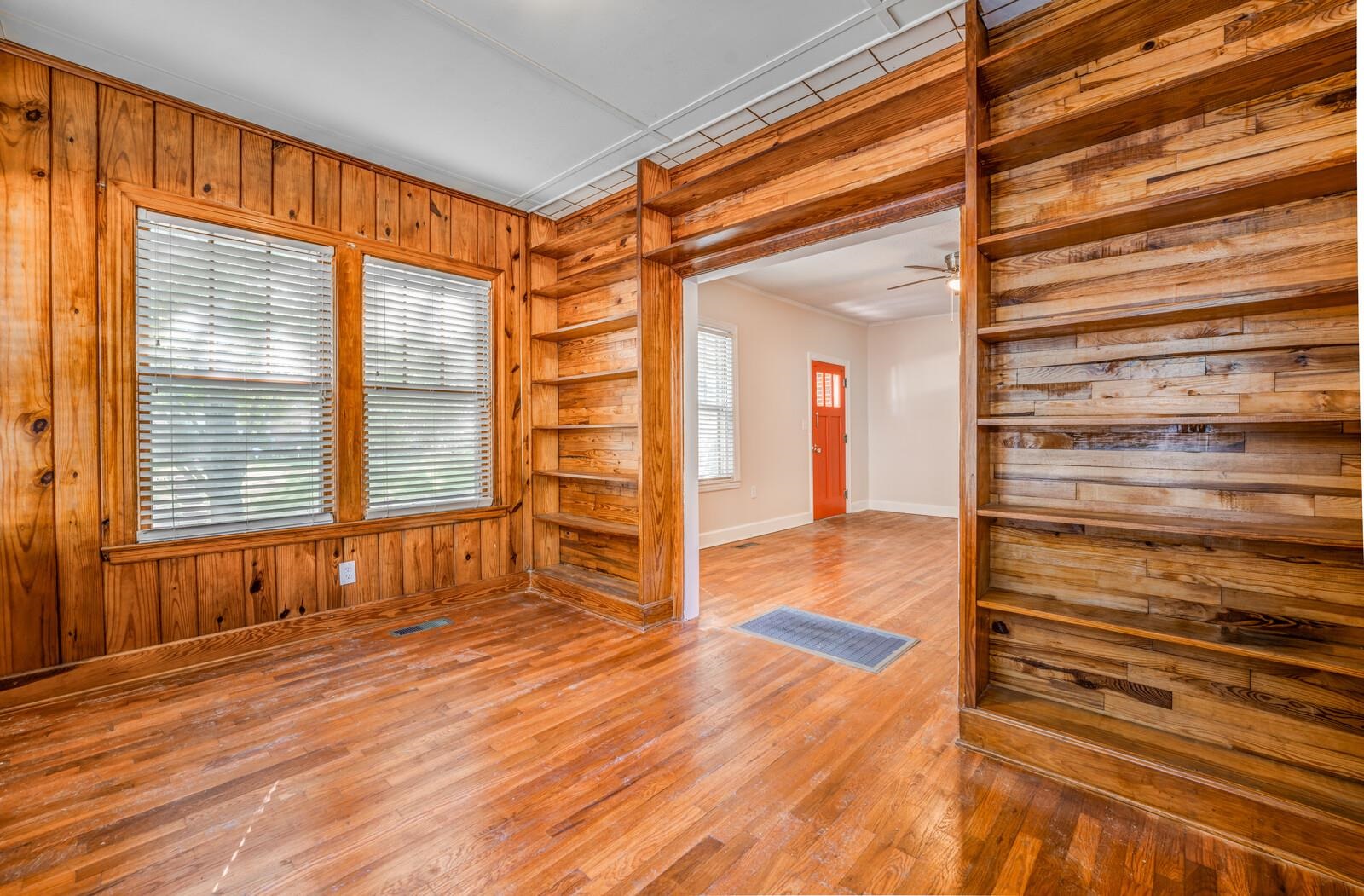 Unfurnished room featuring wooden walls, a healthy amount of sunlight, and hardwood / wood-style floors