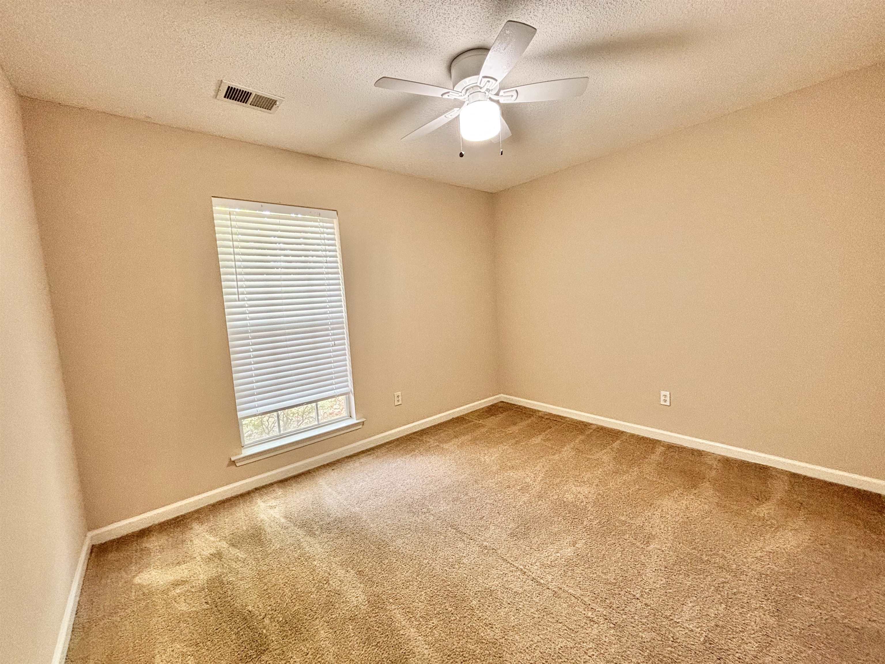 Carpeted empty room featuring ceiling fan and a textured ceiling