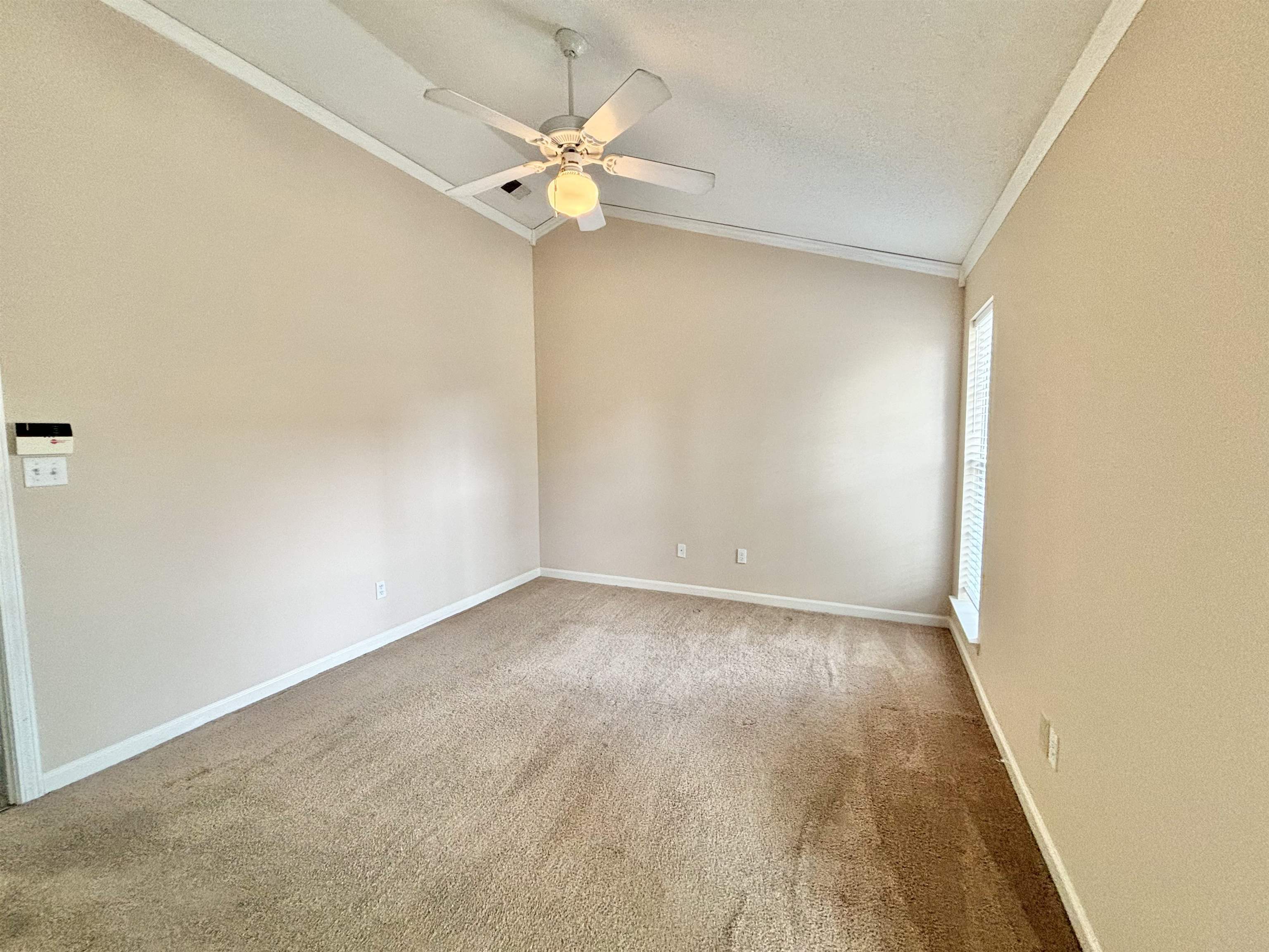 Carpeted spare room with ceiling fan, a textured ceiling, crown molding, and vaulted ceiling