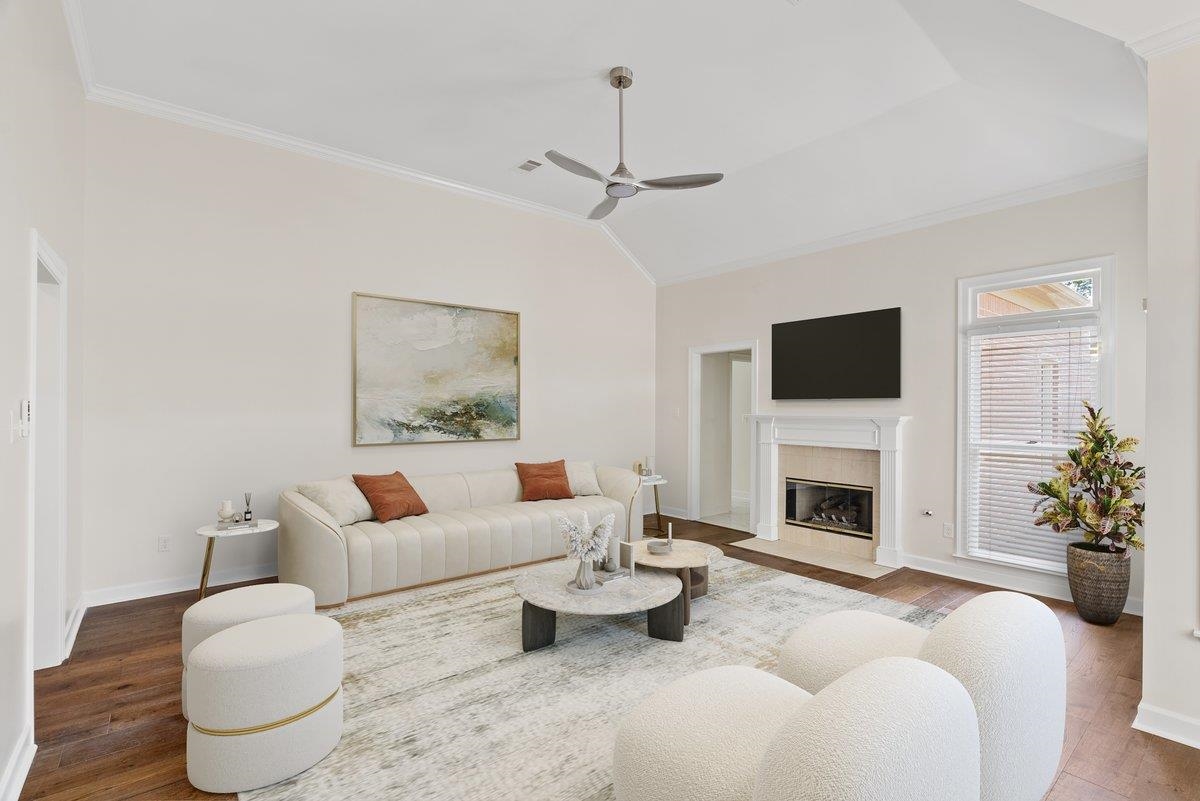 Living room with ceiling fan, ornamental molding, a fireplace, and hardwood / wood-style floors