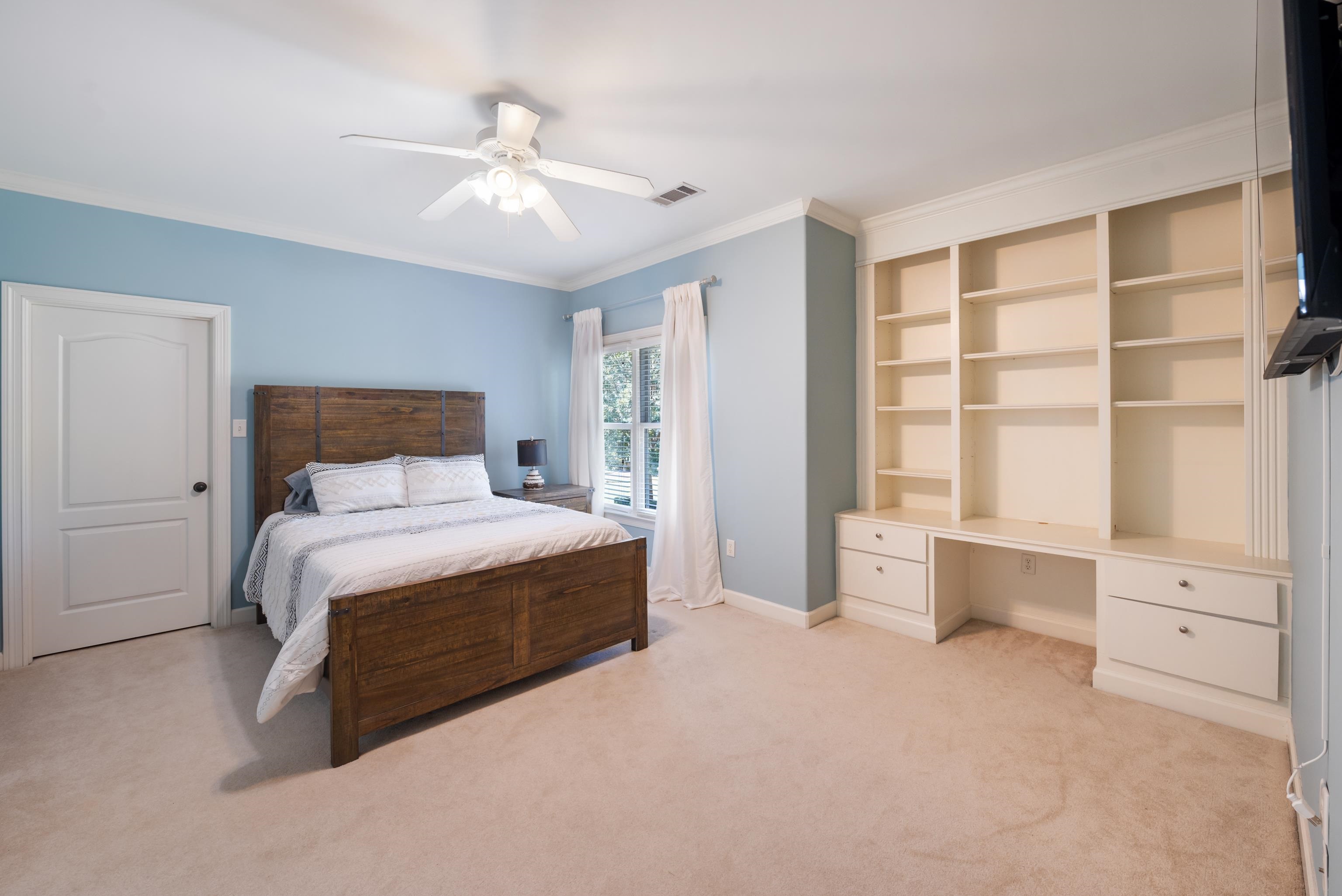 Bedroom with light carpet, ornamental molding, and ceiling fan