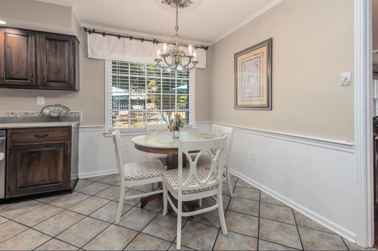 Tiled dining area featuring crown molding and a notable chandelier