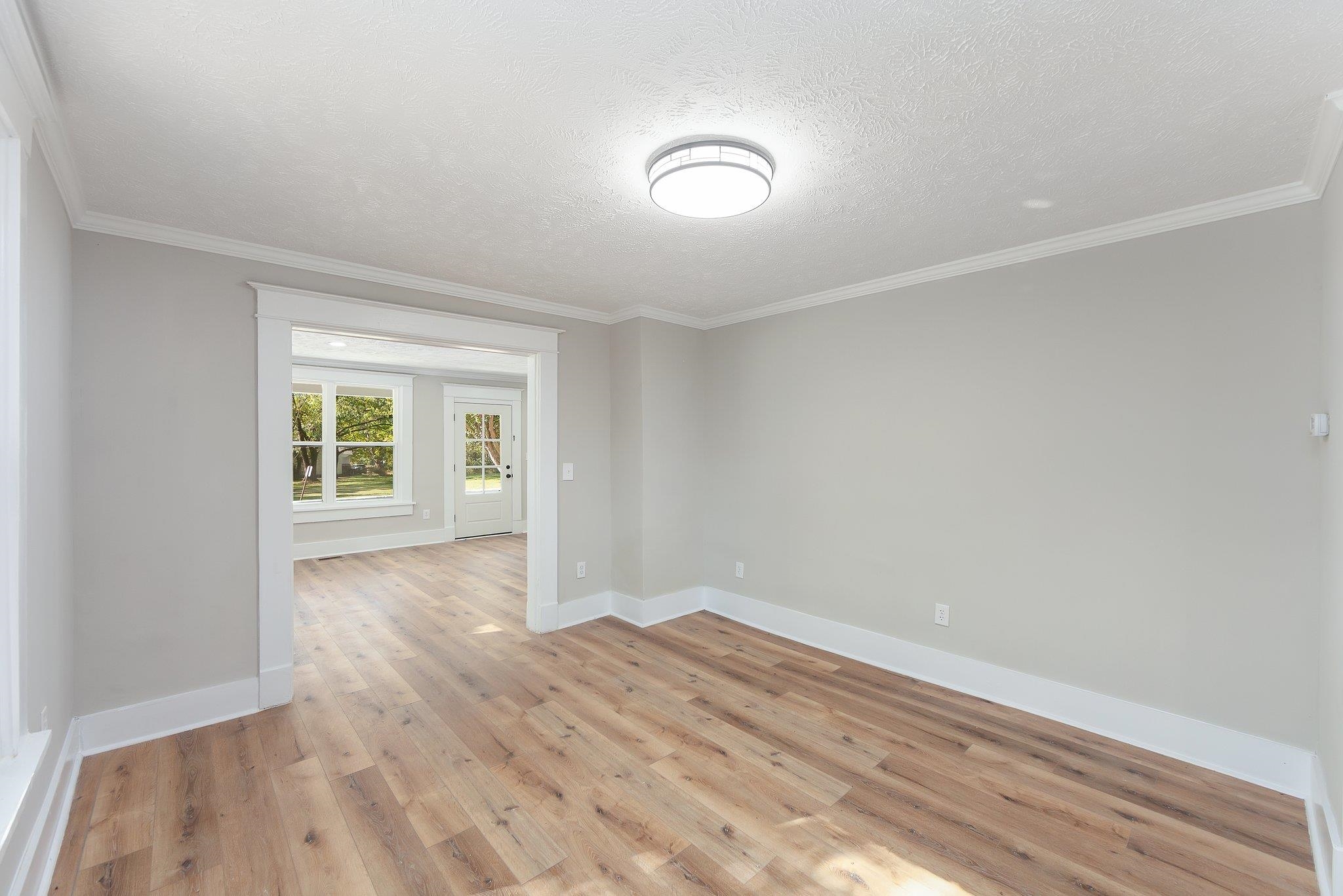 Empty room featuring crown molding, a textured ceiling, and light hardwood / wood-style flooring