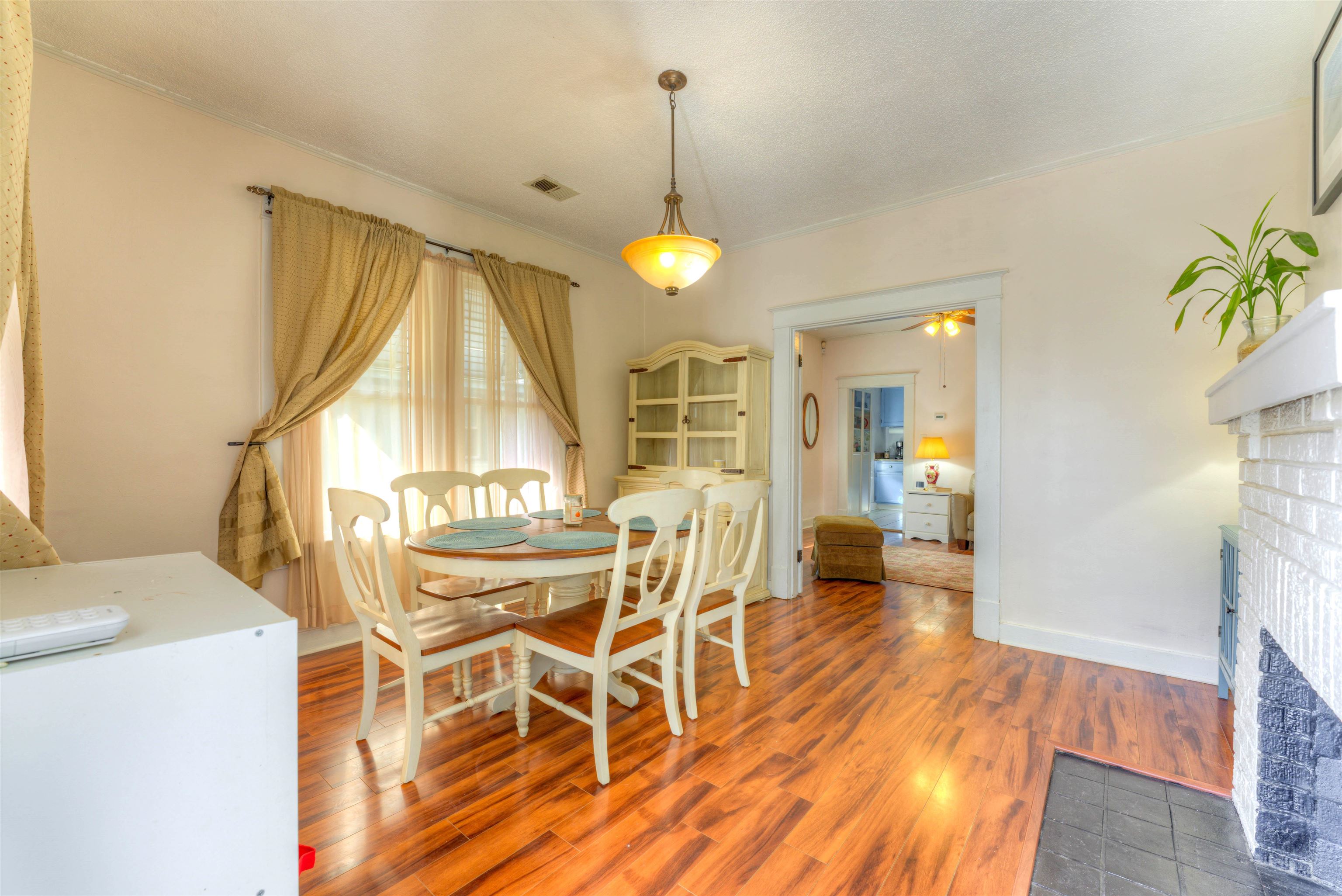 Dining space with a brick fireplace, hardwood / wood-style flooring, and ceiling fan