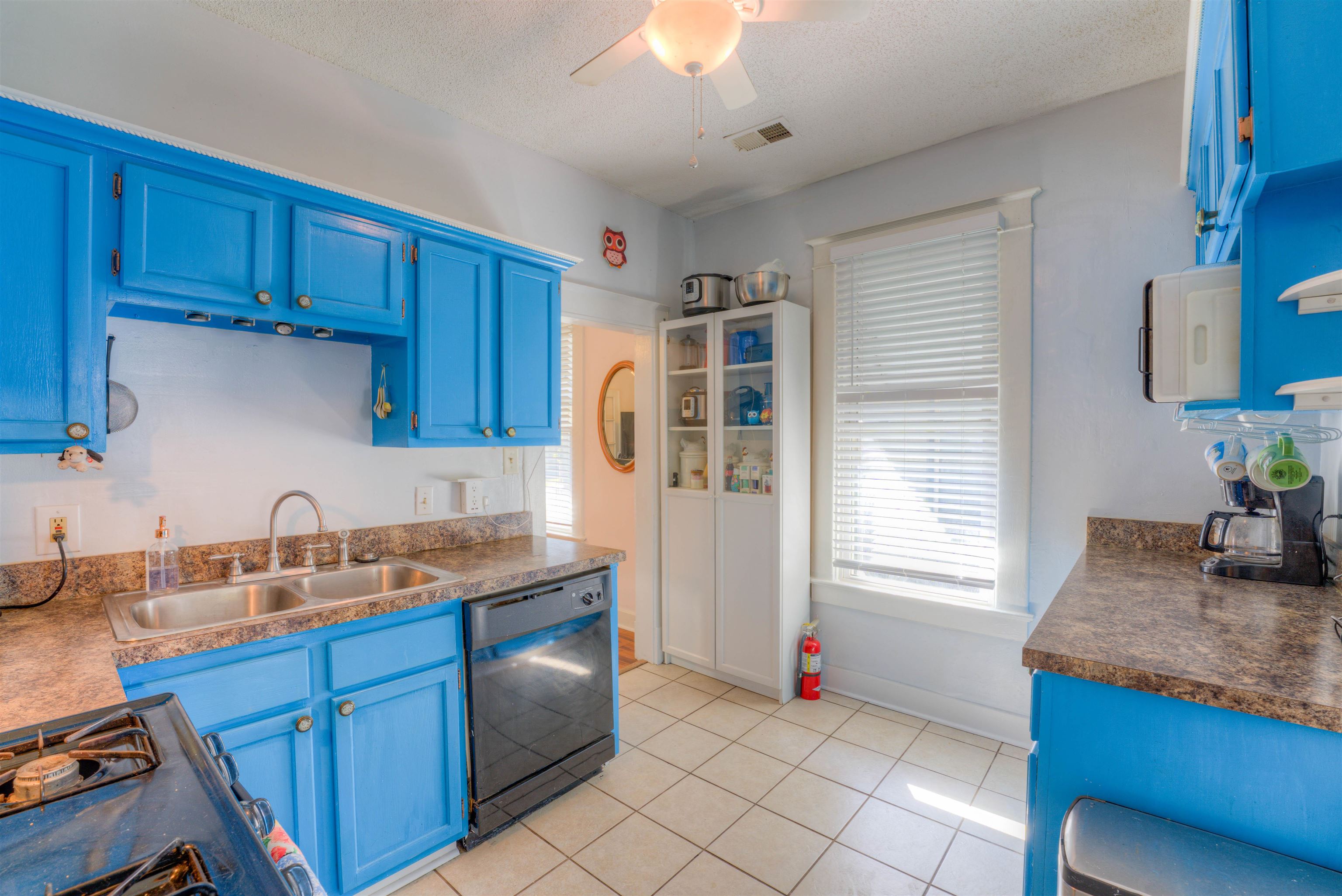 Kitchen featuring blue cabinetry, black dishwasher, sink, and a textured ceiling