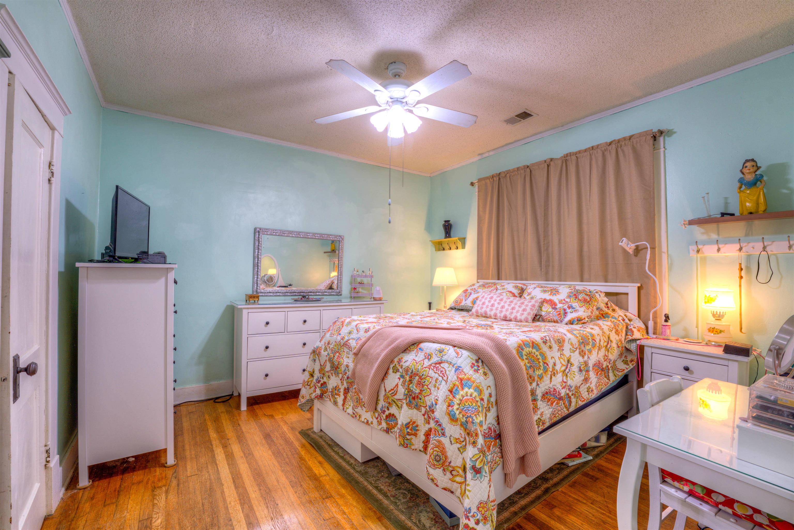 Bedroom with a textured ceiling, ornamental molding, light wood-type flooring, and ceiling fan
