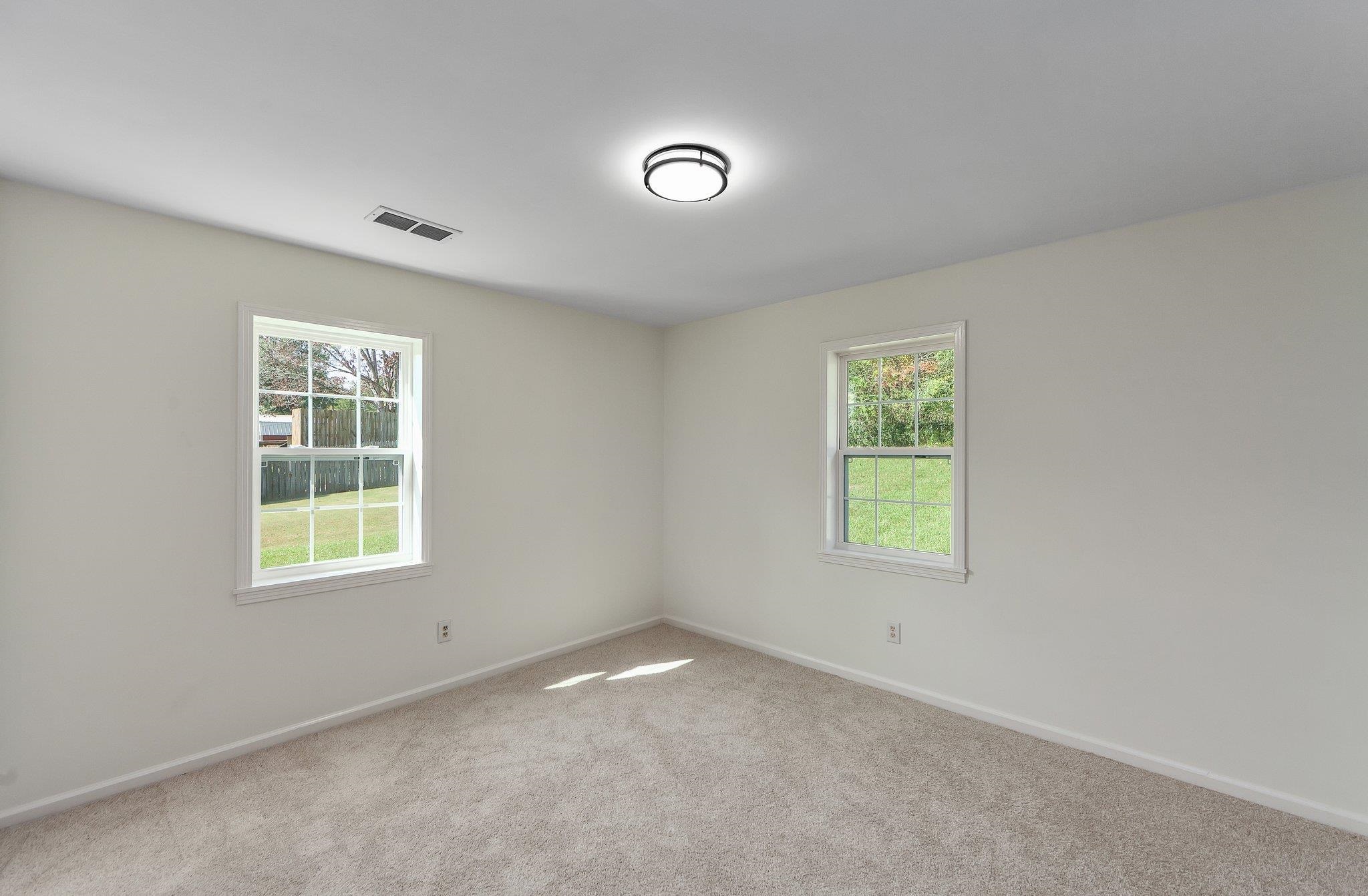 Spare room featuring a wealth of natural light and carpet flooring