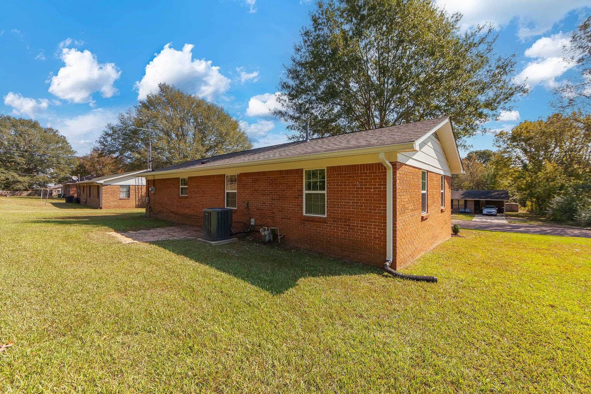 View of side of home with a yard, central air condition unit, and a patio