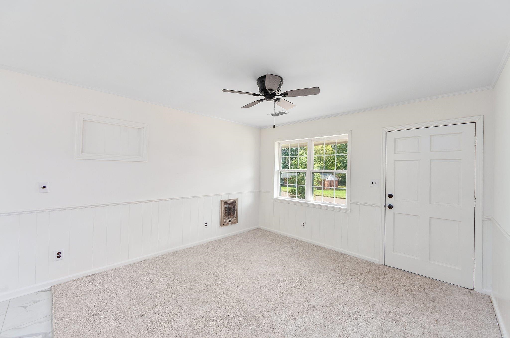 Carpeted spare room featuring ceiling fan and heating unit