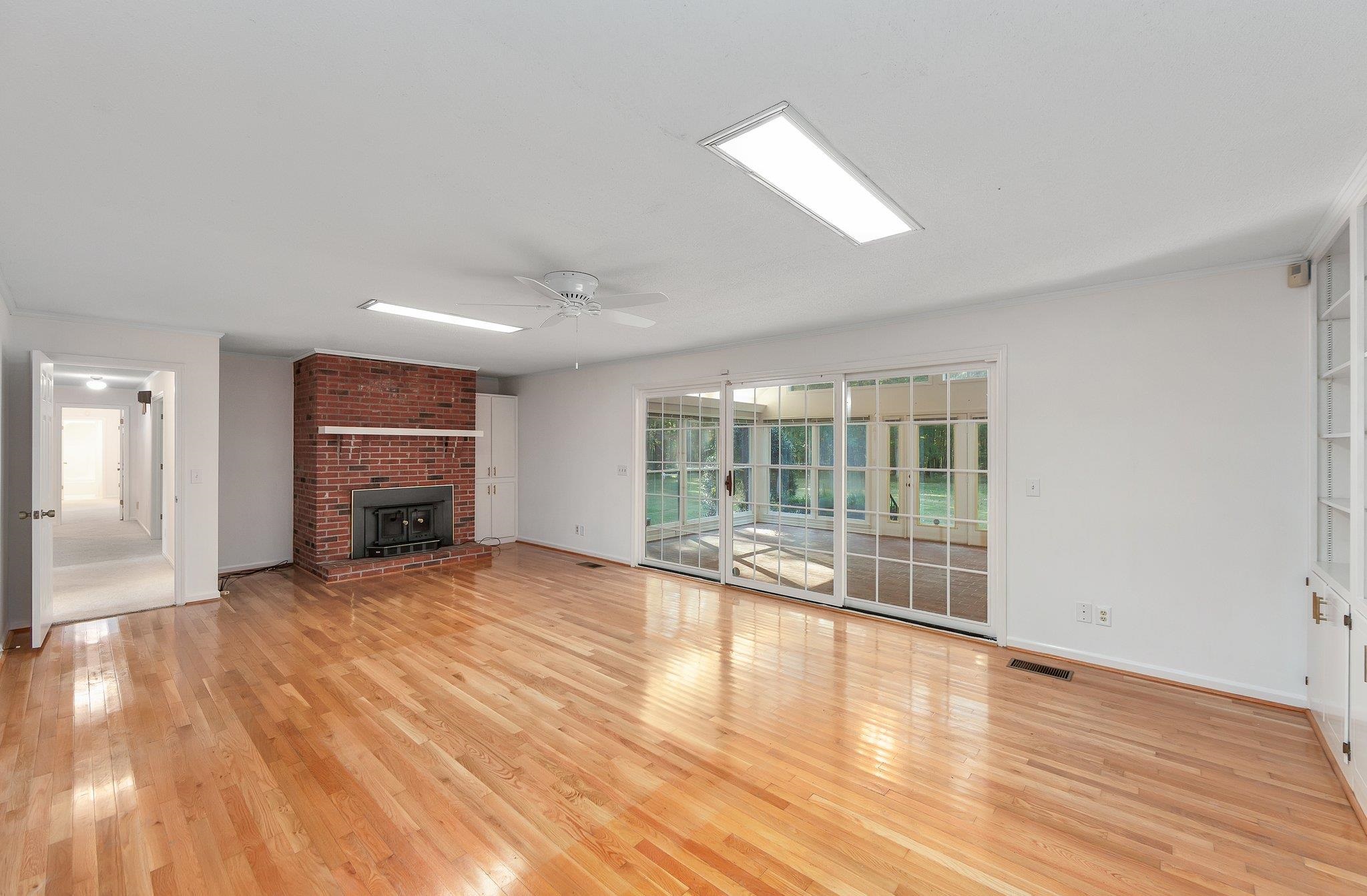 Unfurnished living room with ceiling fan, light hardwood / wood-style floors, and a wood stove