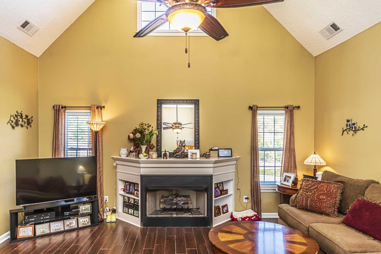 Living room with a textured ceiling, high vaulted ceiling, wood-type flooring, and ceiling fan