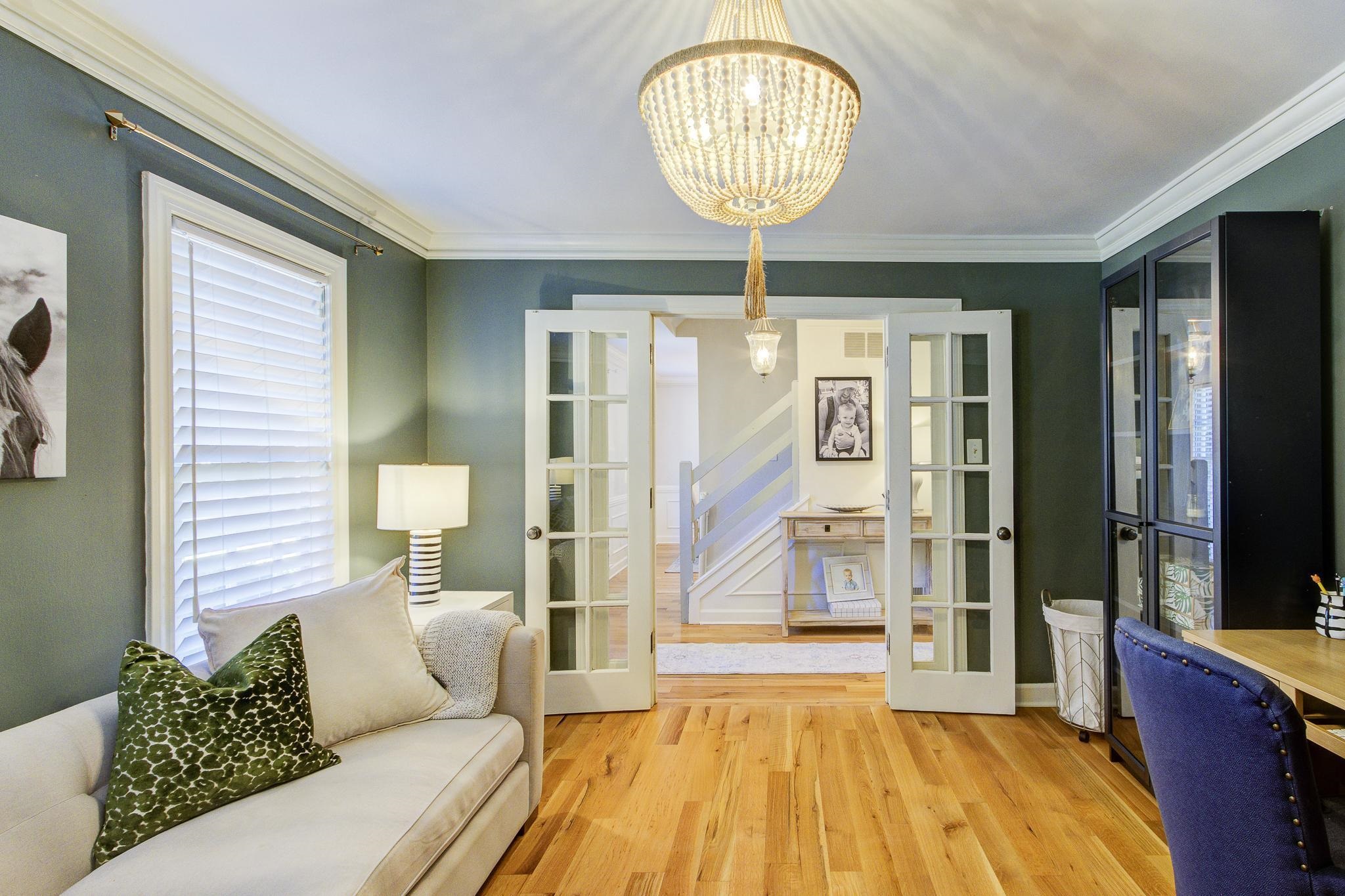 Living room featuring french doors, light hardwood / wood-style floors, crown molding, and an inviting chandelier