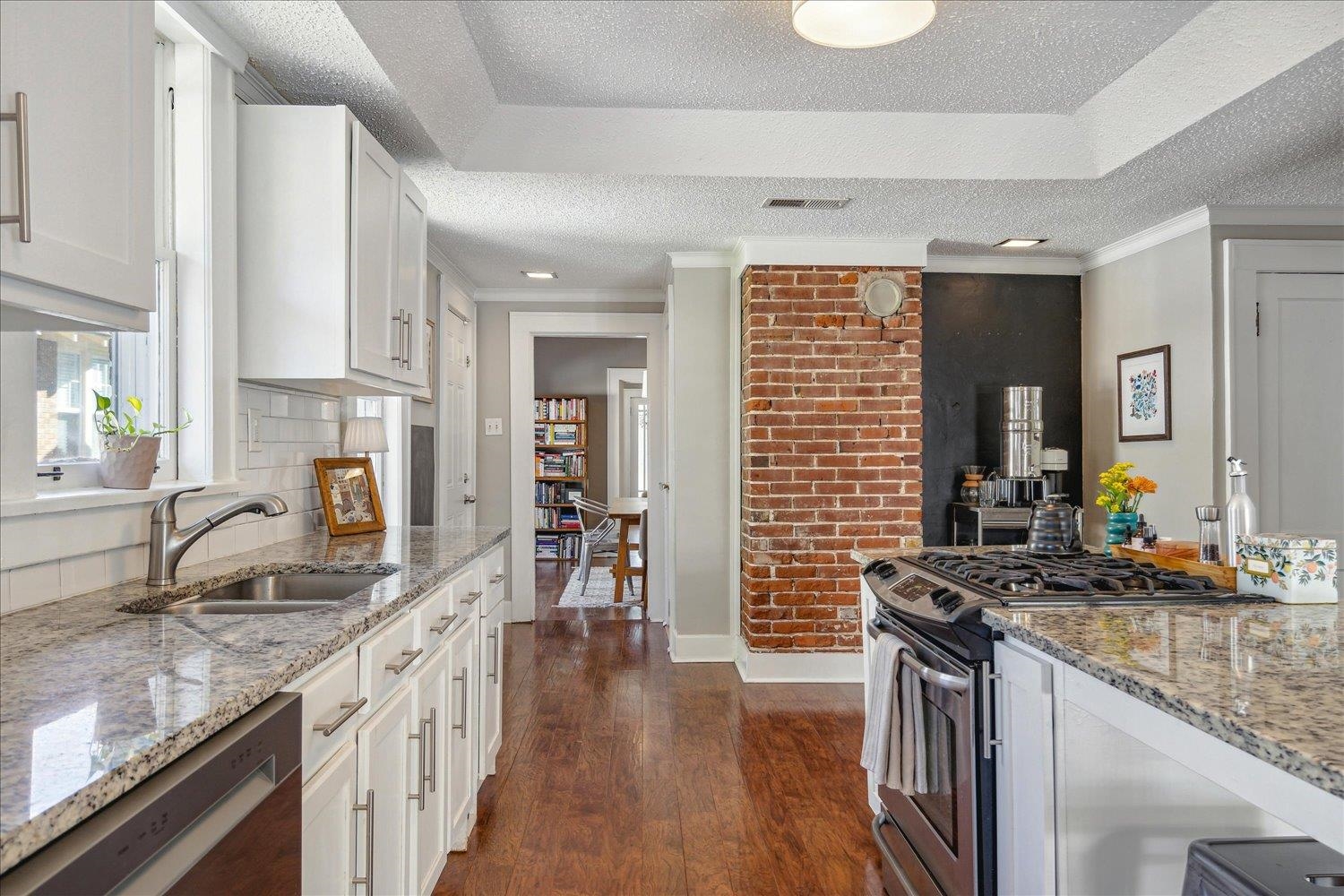 Kitchen featuring hardwood flooring, stainless steel appliances, breakfast bar, and ample storage.