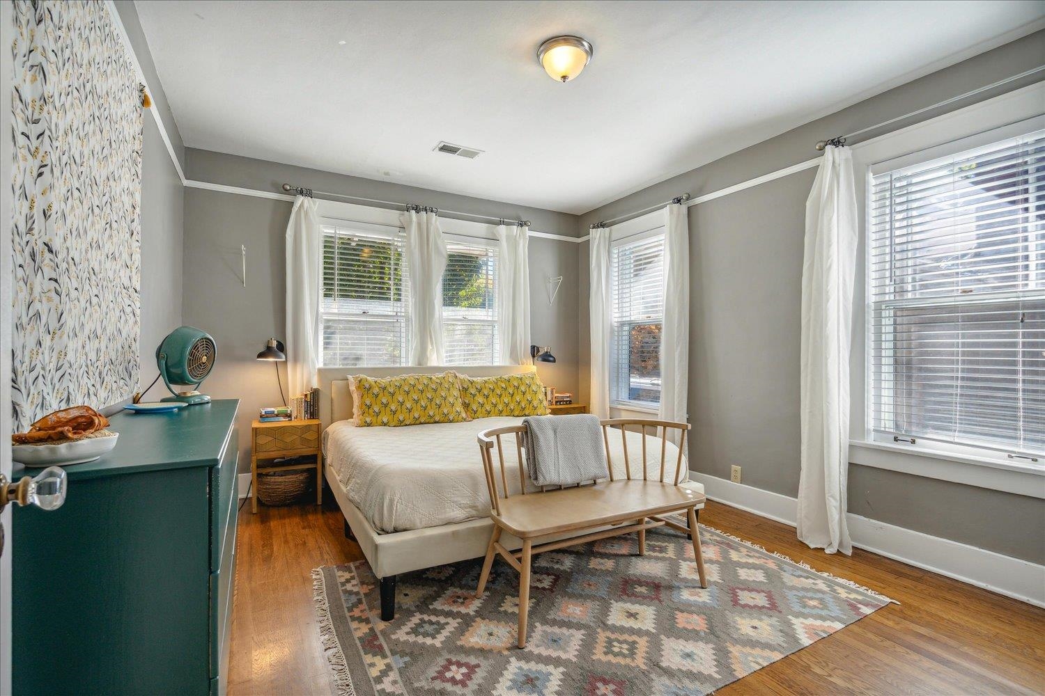 Primary bedroom with multiple windows and hardwood flooring.