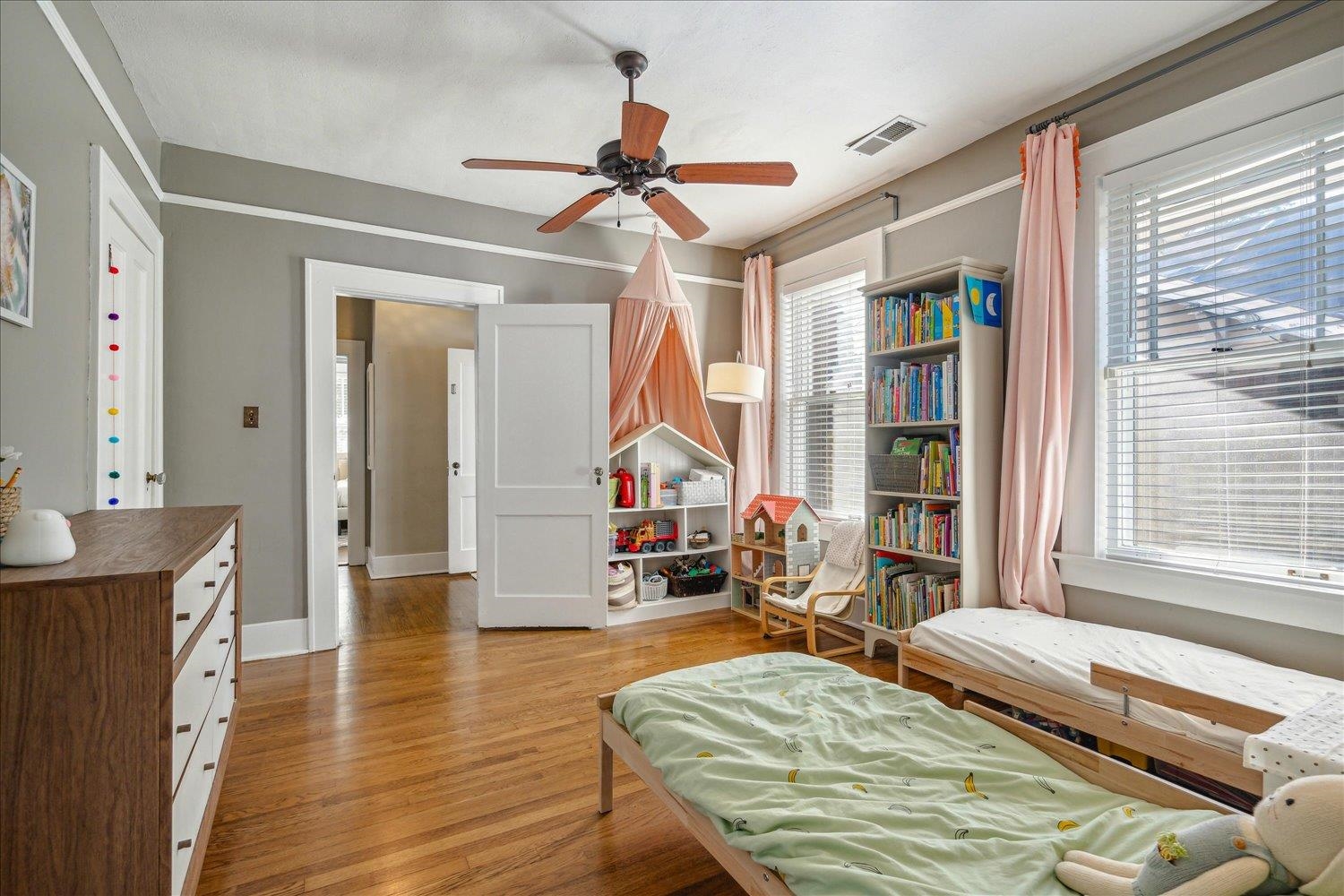 Bedroom with a wealth of natural light, light hardwood floors, and ceiling fan.