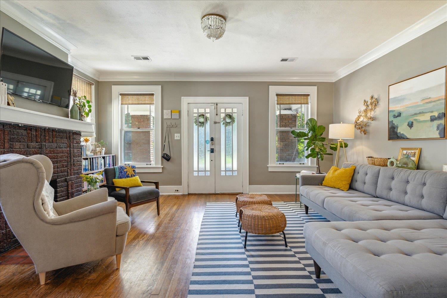 Living room featuring crown molding, french doors, dark wood-type flooring, and a brick fireplace