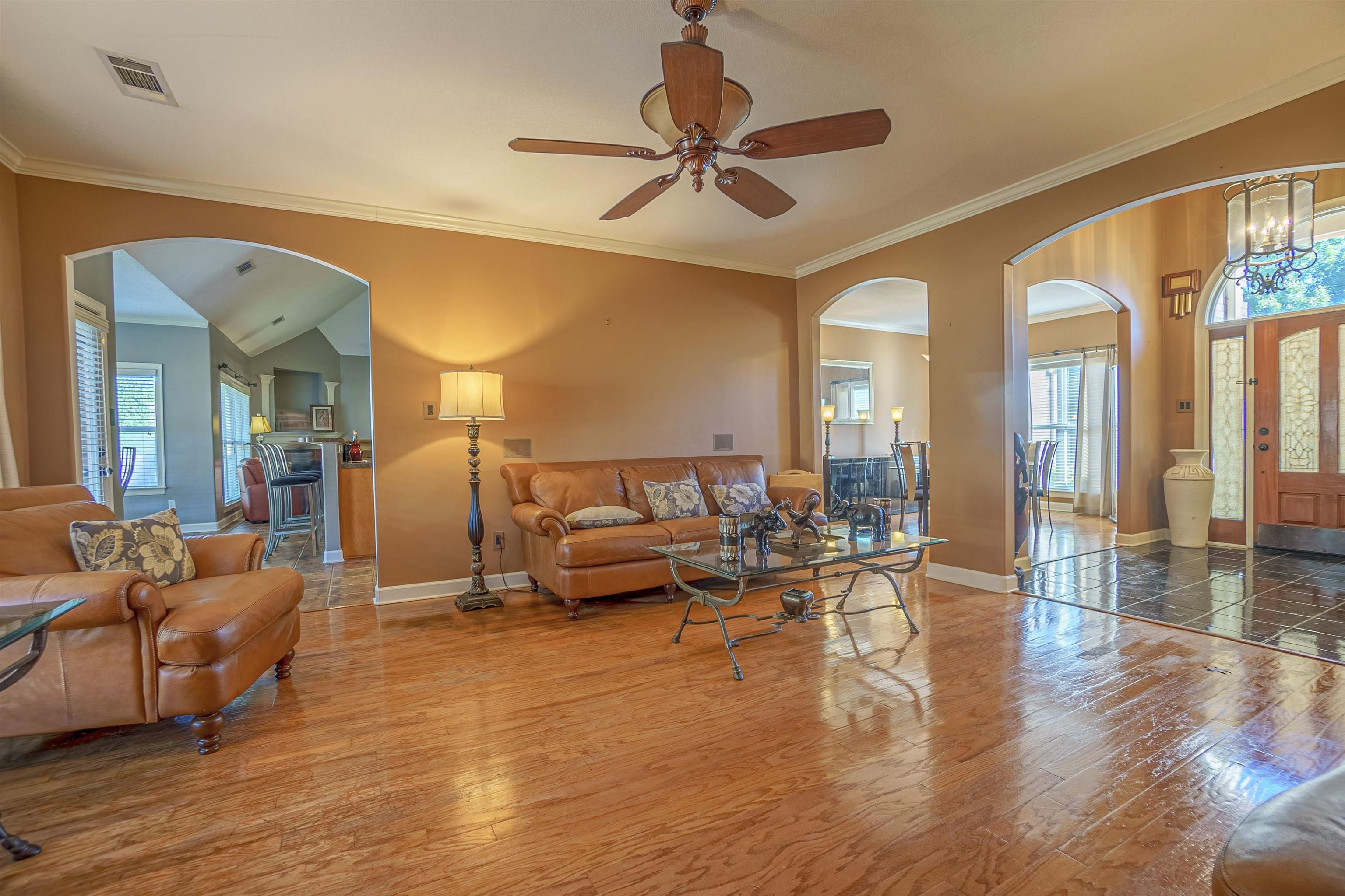 Living room featuring hardwood / wood-style floors, crown molding, and ceiling fan with notable chandelier