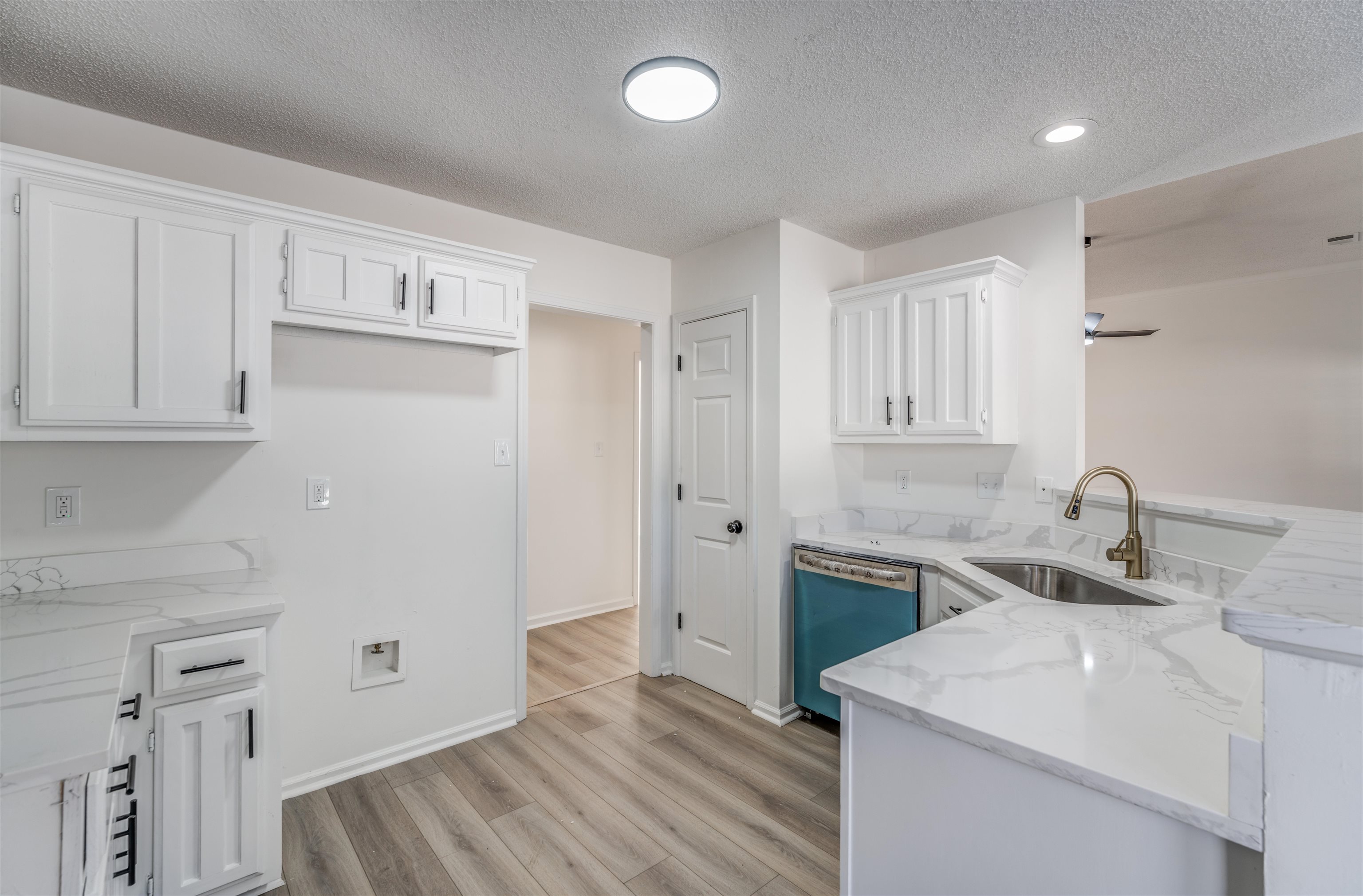 Kitchen featuring stainless steel dishwasher, white cabinets, kitchen peninsula, and light hardwood / wood-style floors