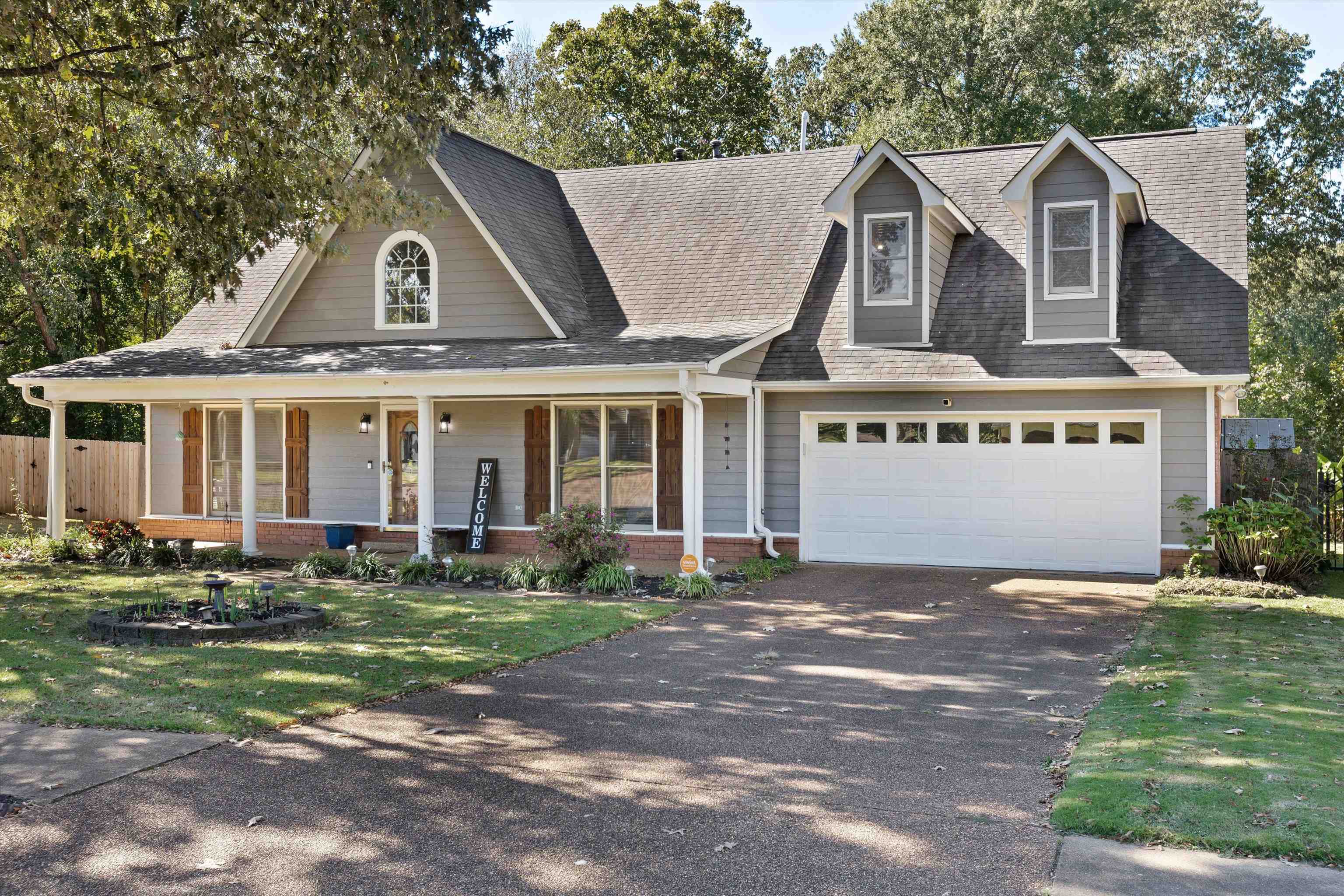 View of front facade featuring covered porch, a garage, and a front lawn