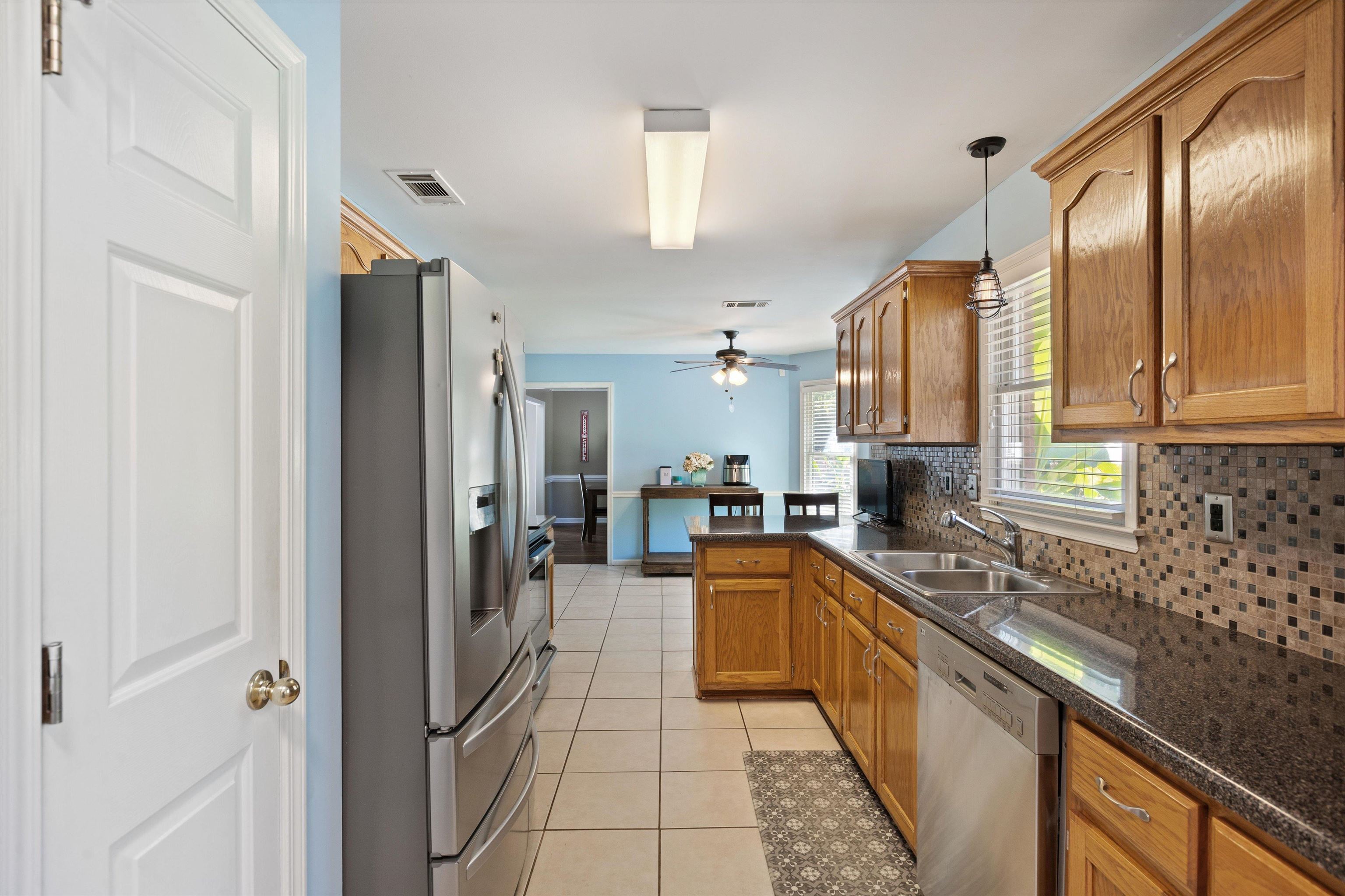 Kitchen with kitchen peninsula, tasteful backsplash, hanging light fixtures, sink, and stainless steel appliances