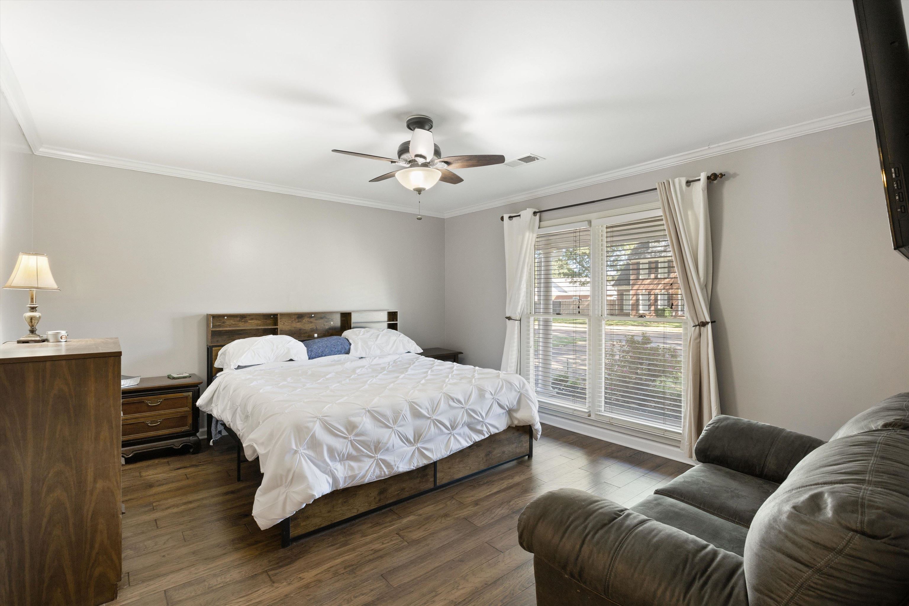 Bedroom with ornamental molding, ceiling fan, and dark hardwood / wood-style flooring
