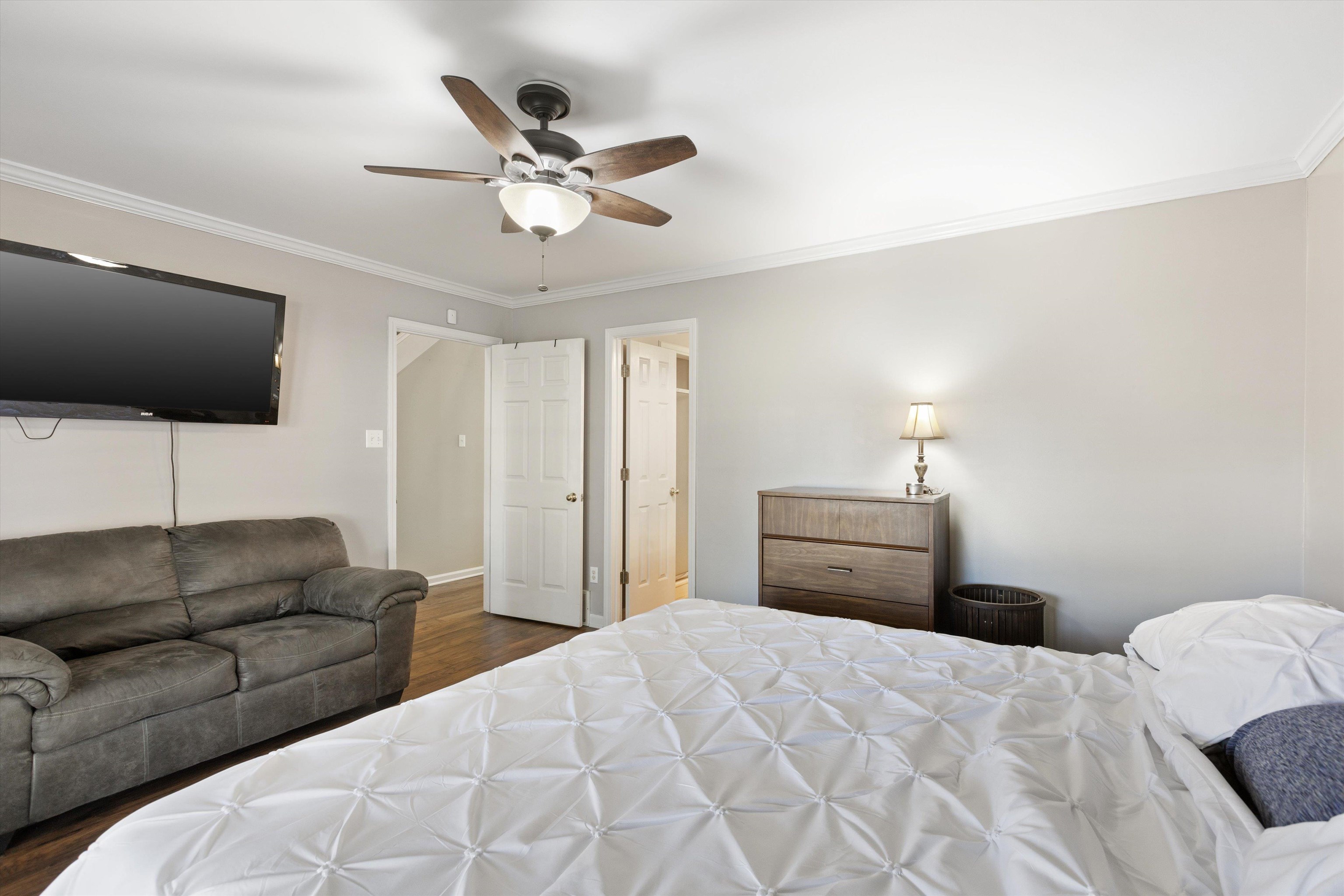 Bedroom with ceiling fan, ornamental molding, and dark hardwood / wood-style floors