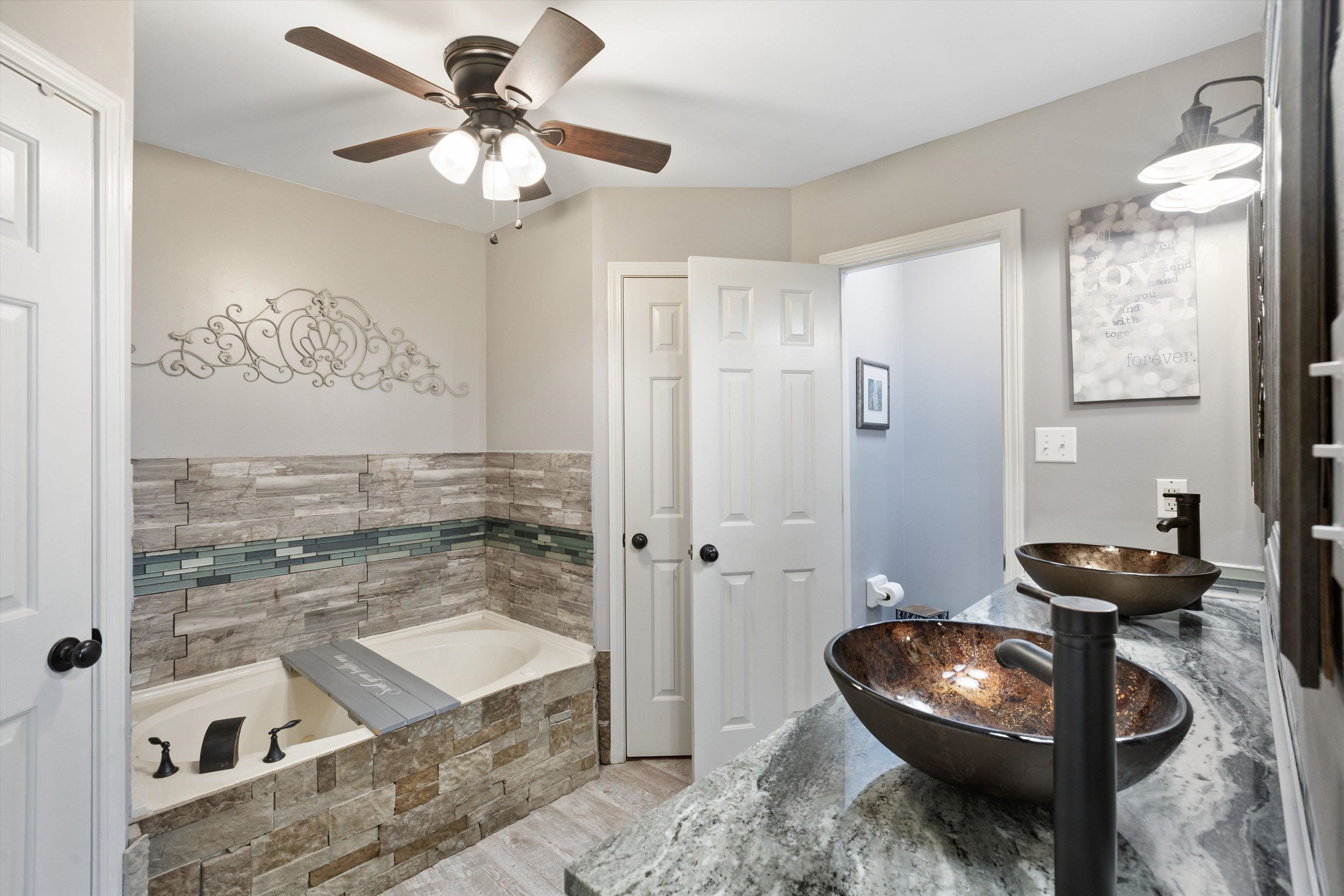 Bathroom with vanity, hardwood / wood-style flooring, tiled tub, and ceiling fan