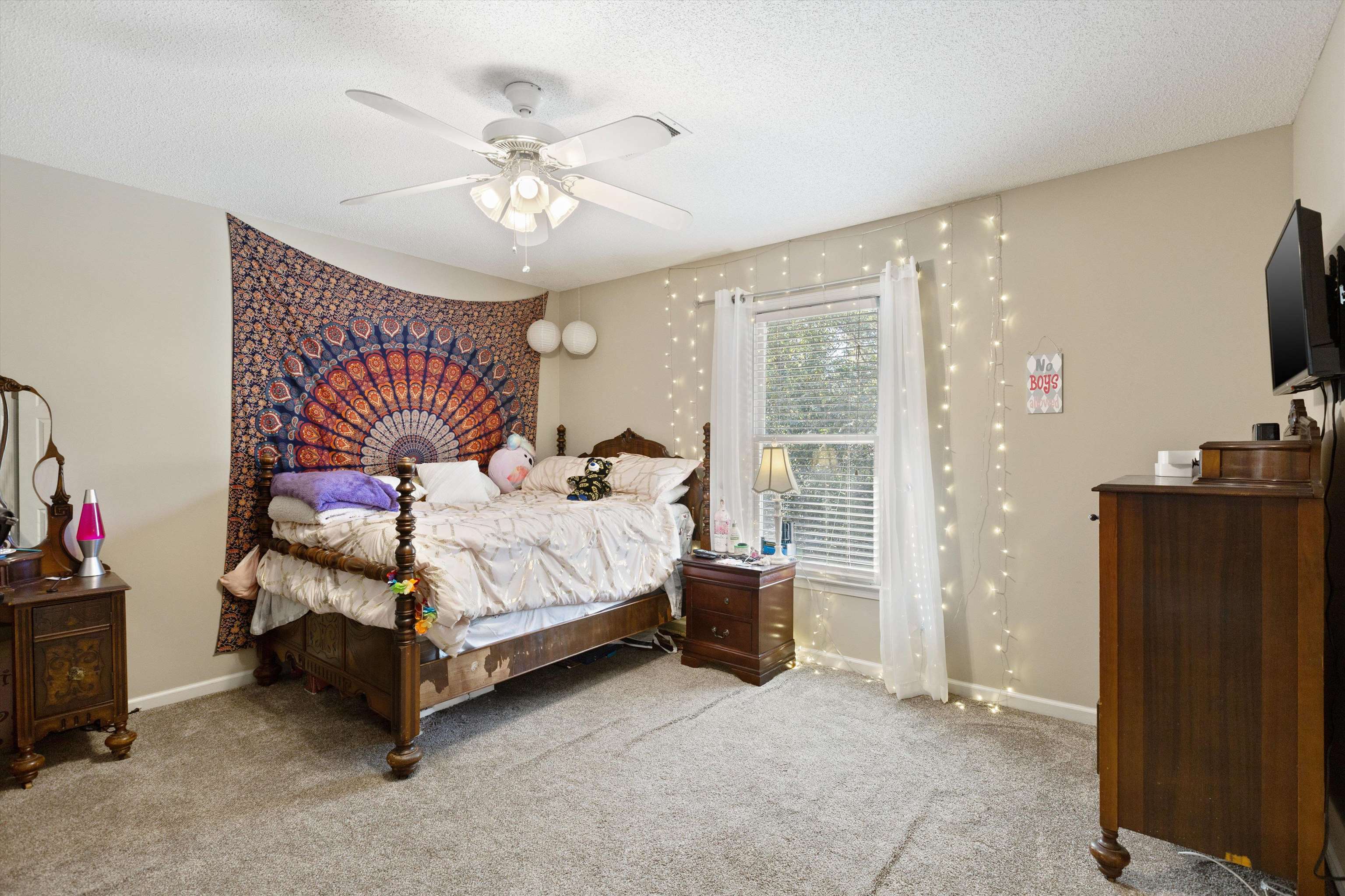 Bedroom with a textured ceiling, light colored carpet, and ceiling fan