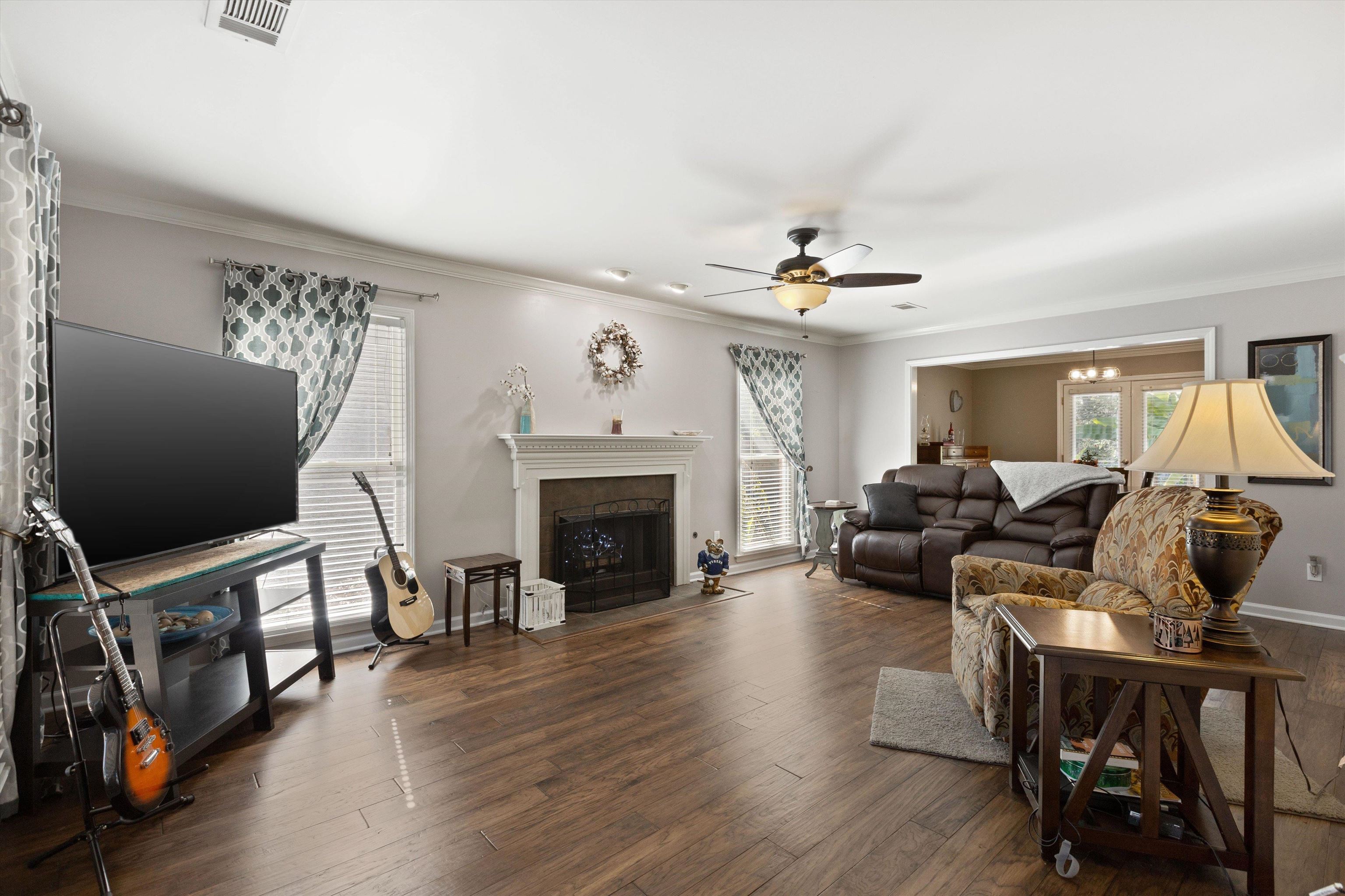Living room with ceiling fan, ornamental molding, and dark hardwood / wood-style floors