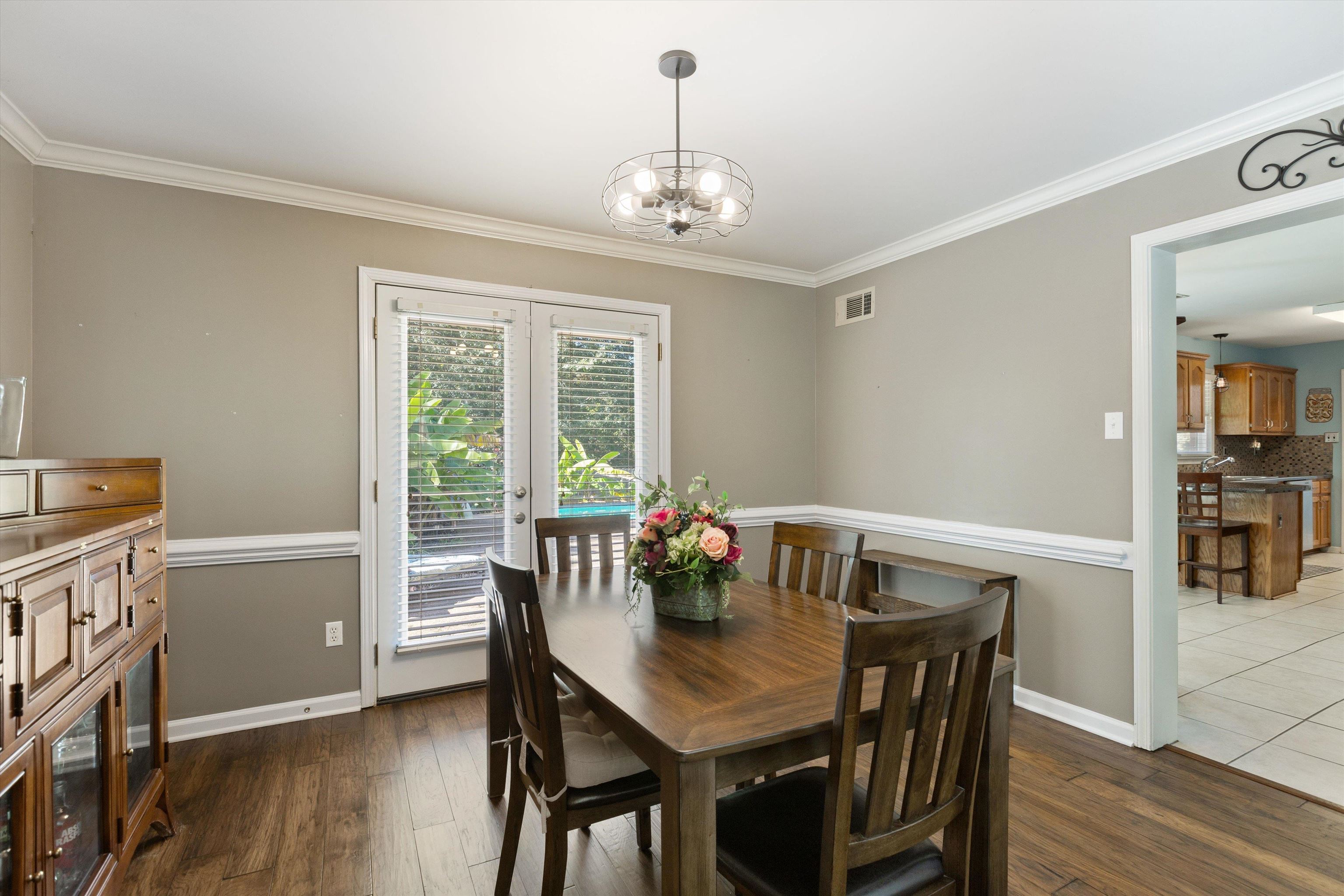 Dining room featuring dark wood-type flooring, crown molding, a chandelier, and french doors